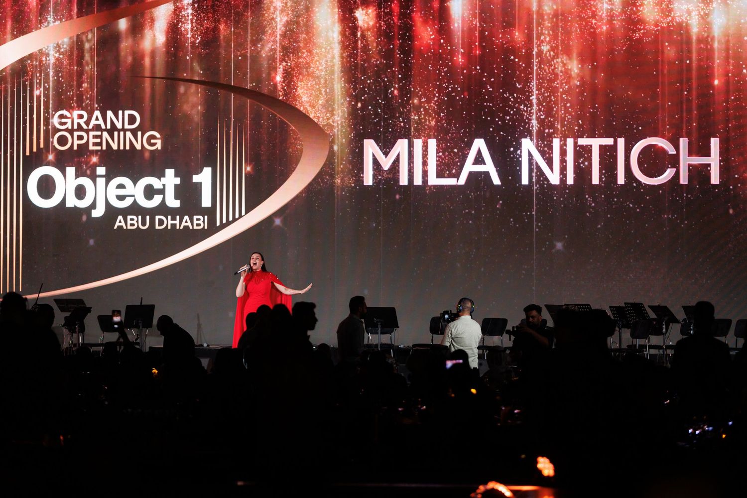 Concert venue illuminated in dramatic red lighting with text displays showing 