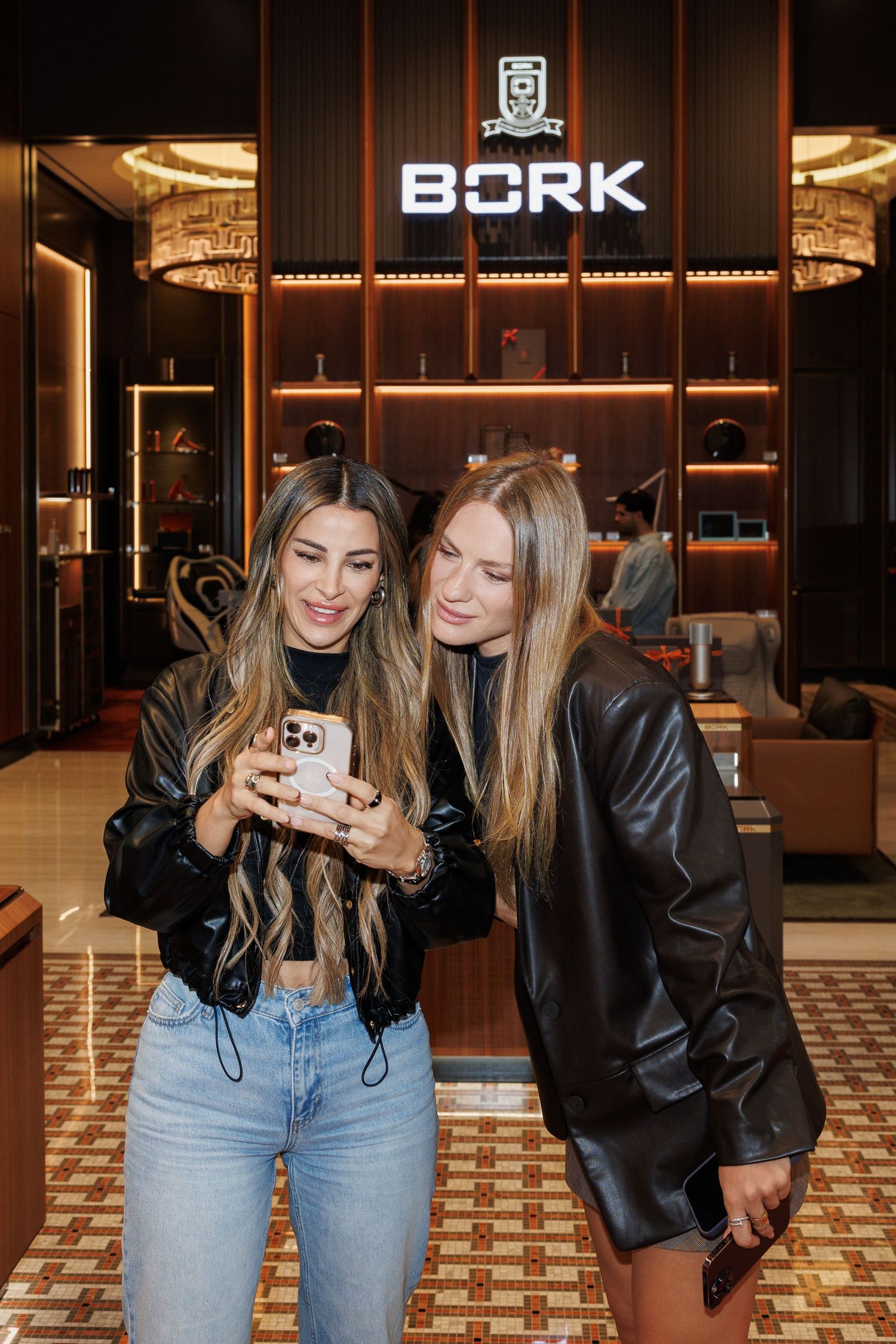 Friends in leather jackets and jeans taking selfies in front of BORK store signage.