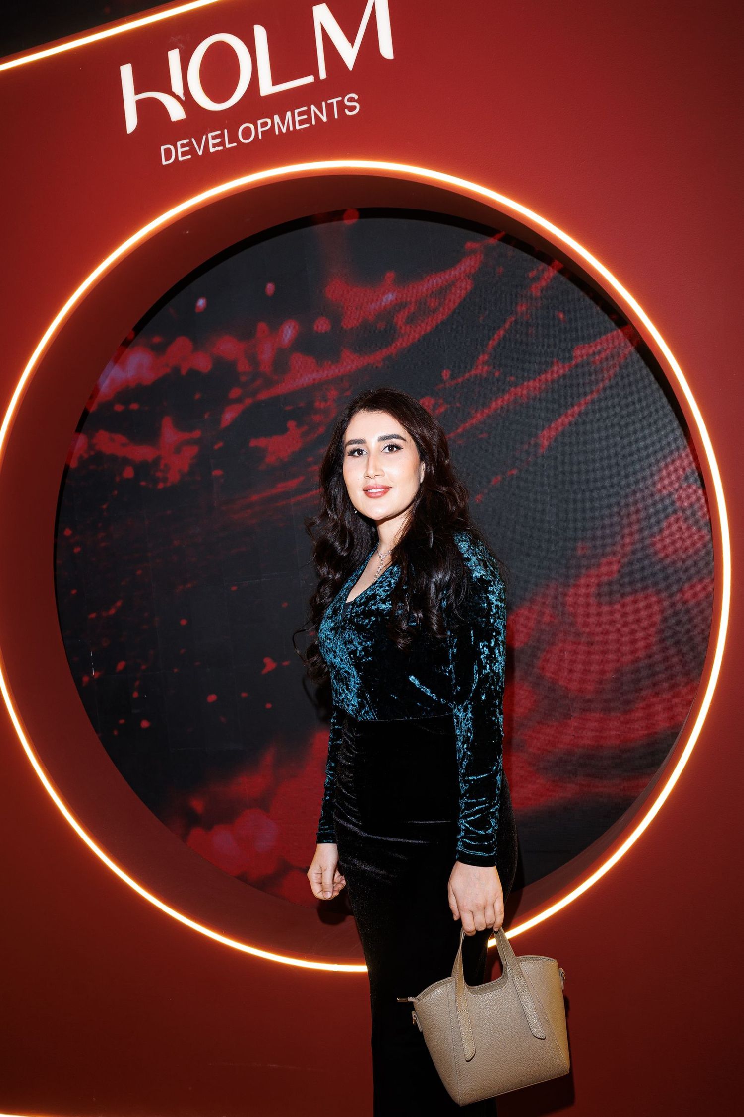 Fashion show backdrop with KOLM branding featuring an oval illuminated frame against red lighting.