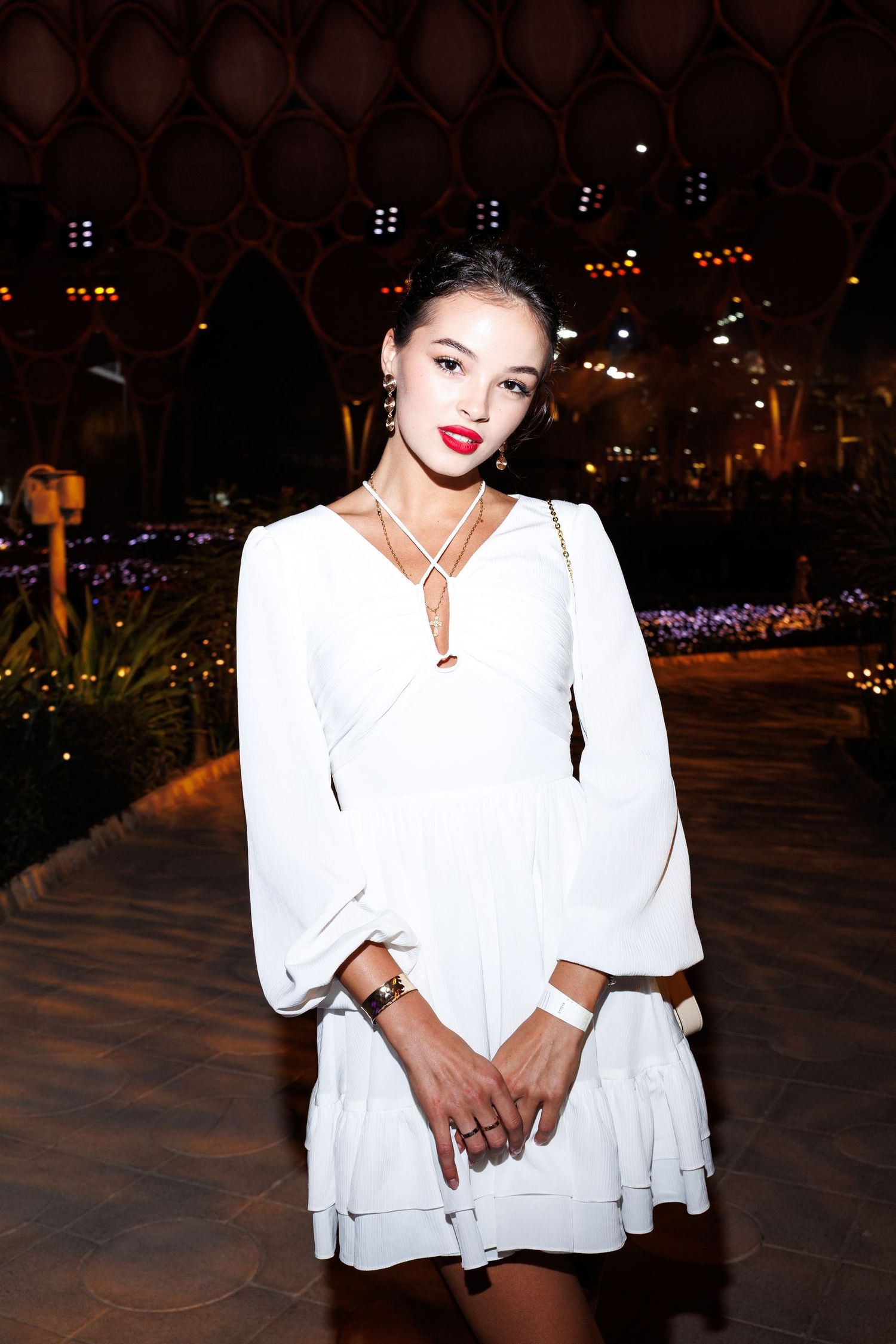 Woman in white outfit poses at night with dramatic lighting and urban backdrop.