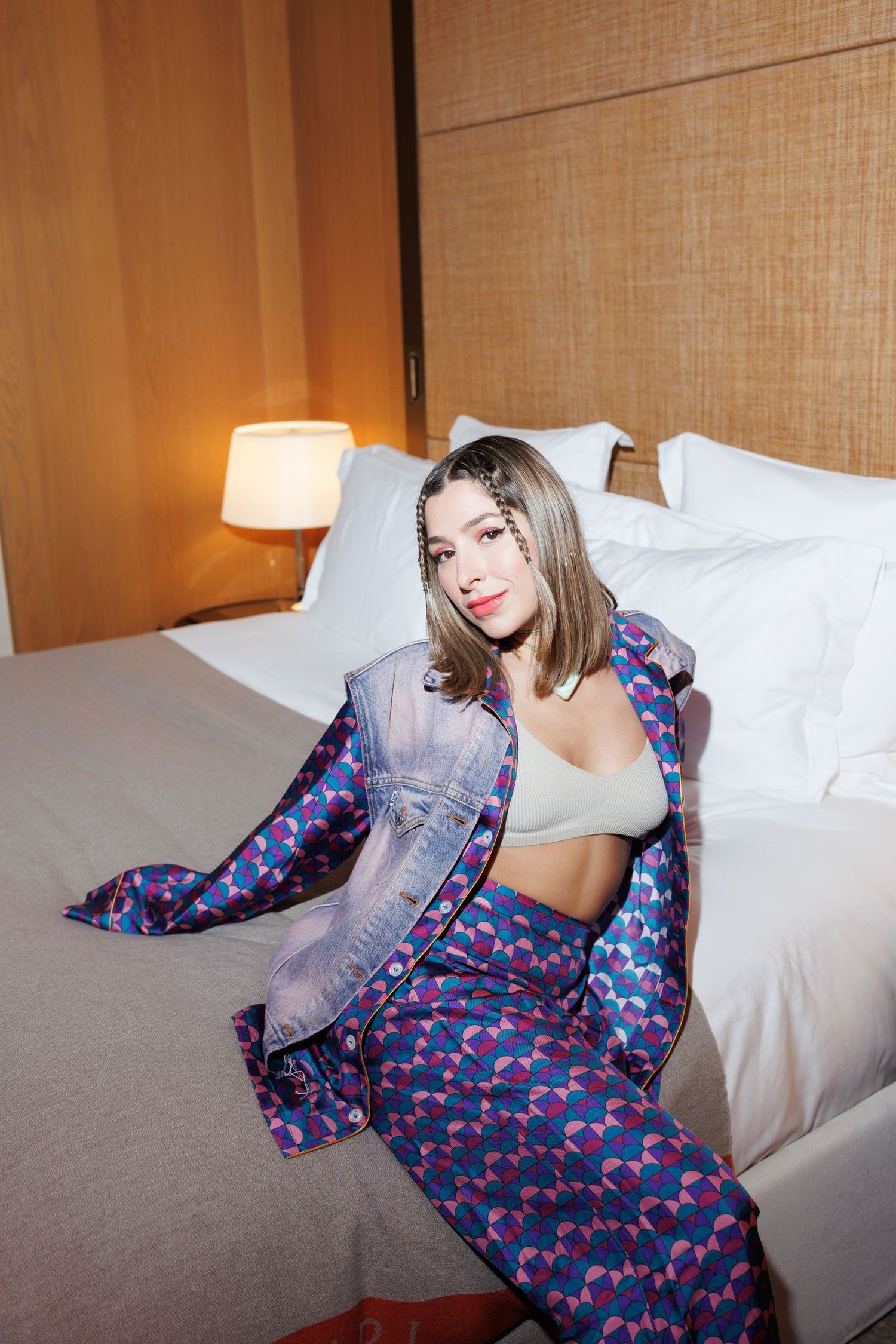 Person in blue floral pajamas lounging on white hotel bed.