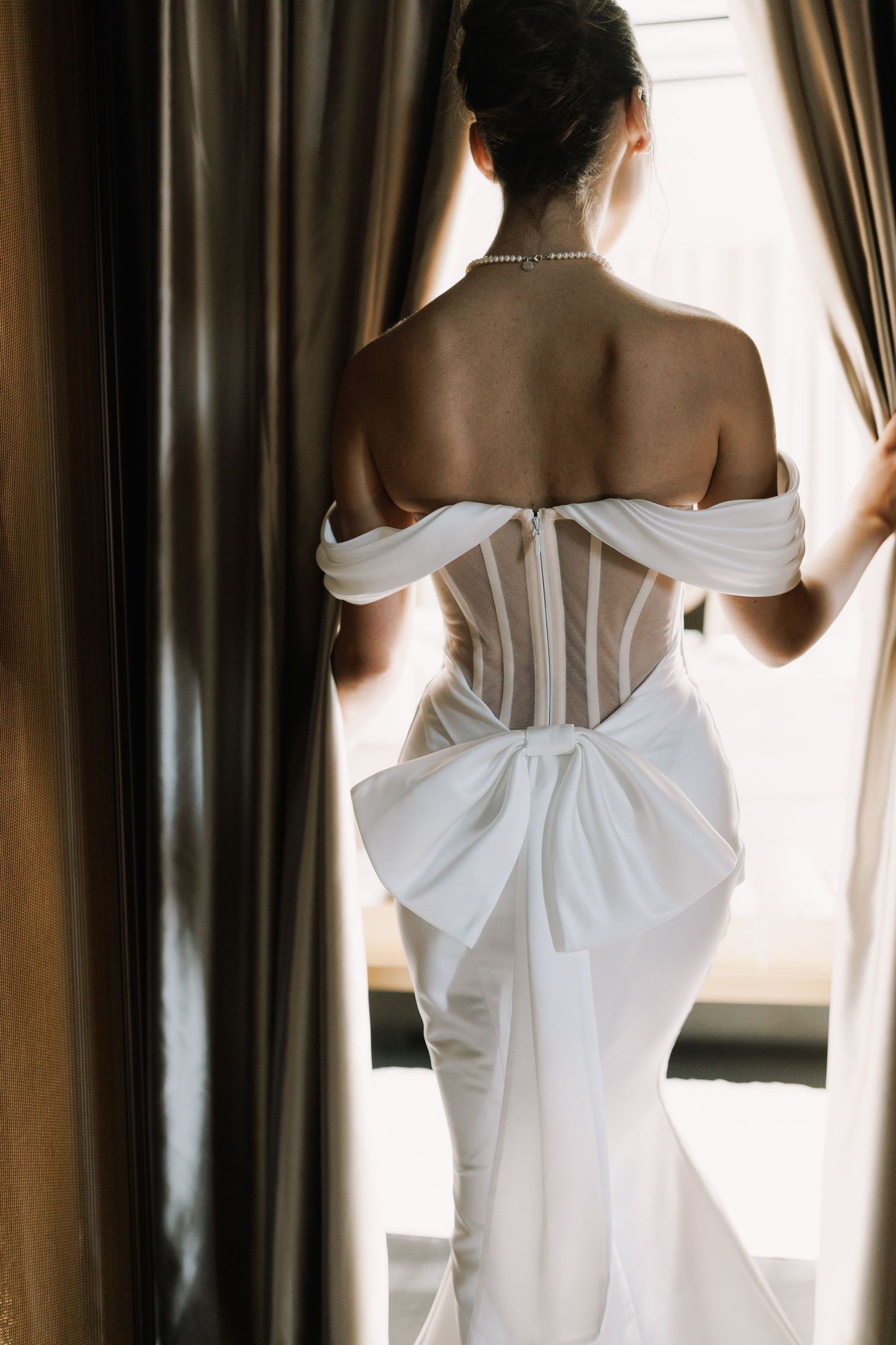 Detailed back view of a white corset wedding gown with off-shoulder design.