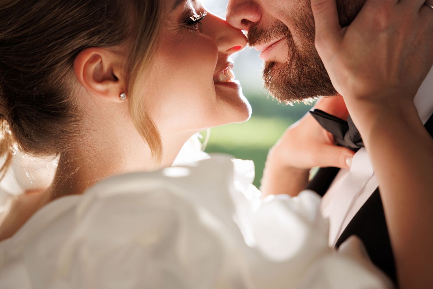 Intimate close-up of romantic wedding moment outdoors.
