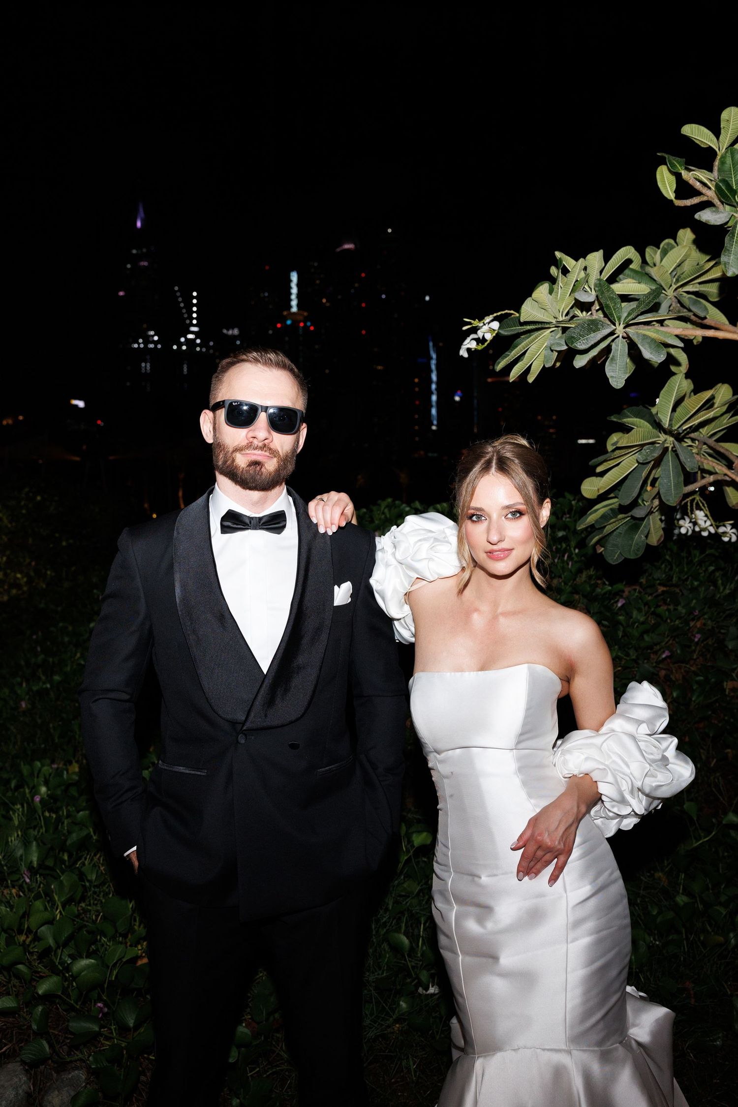 Newlyweds pose for nighttime portraits in formal wedding attire.