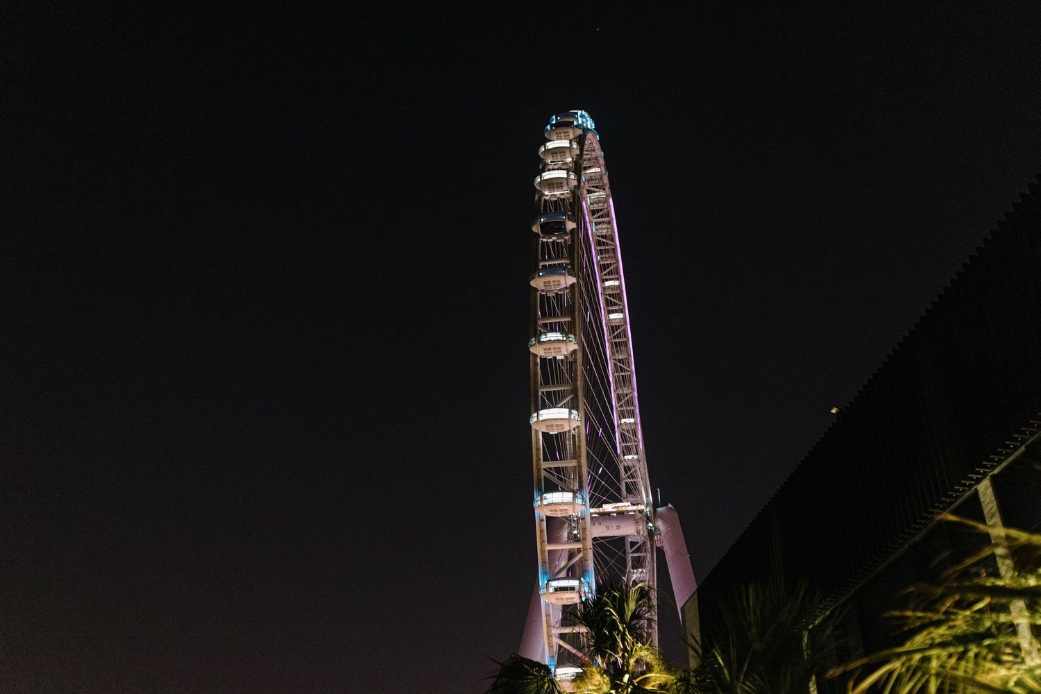 Illuminated Ferris wheel against dark night sky at Dubai festival.