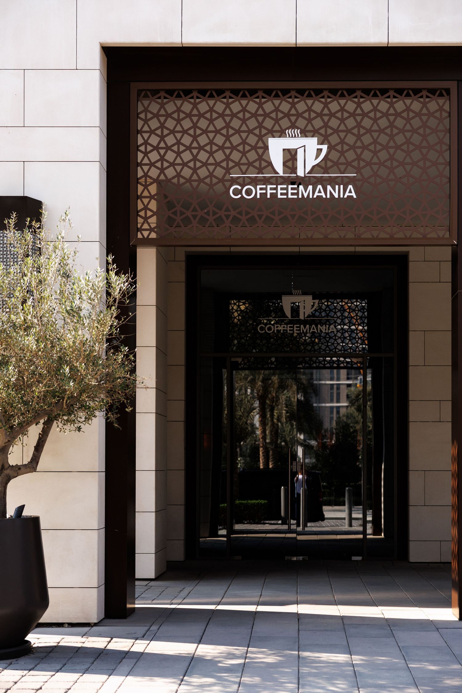 Exterior storefront of Coffeemania cafe with modern architectural design and glass windows.