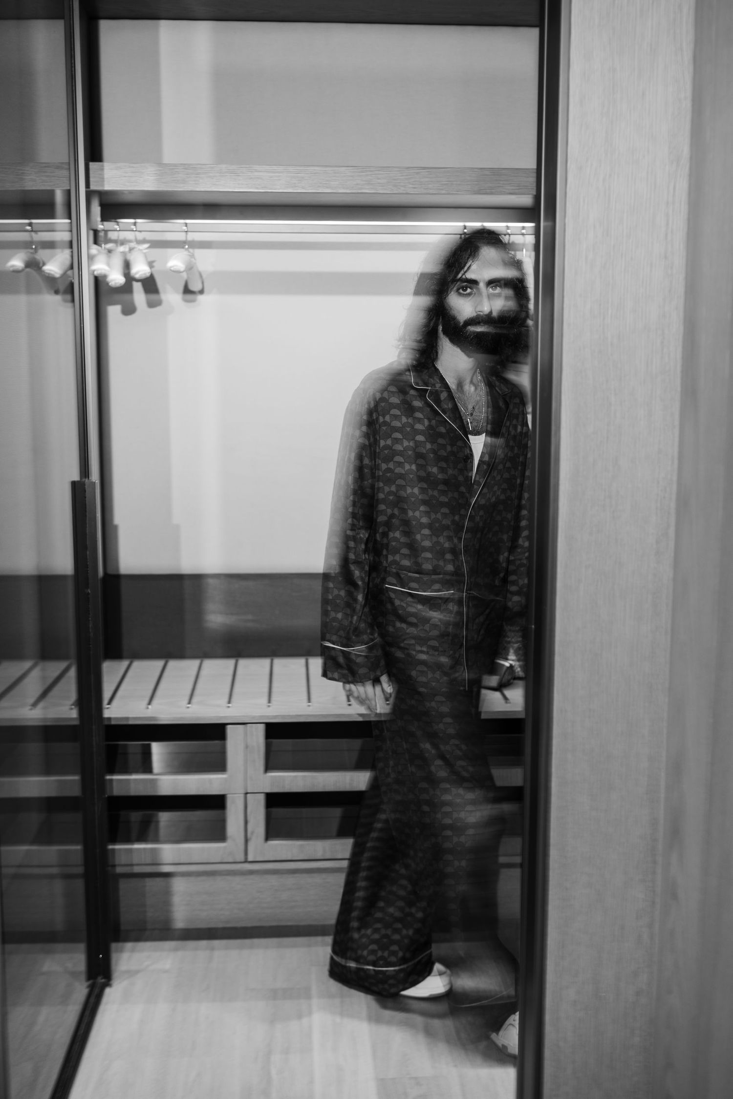 Black and white photo of someone walking through a modern interior hallway.