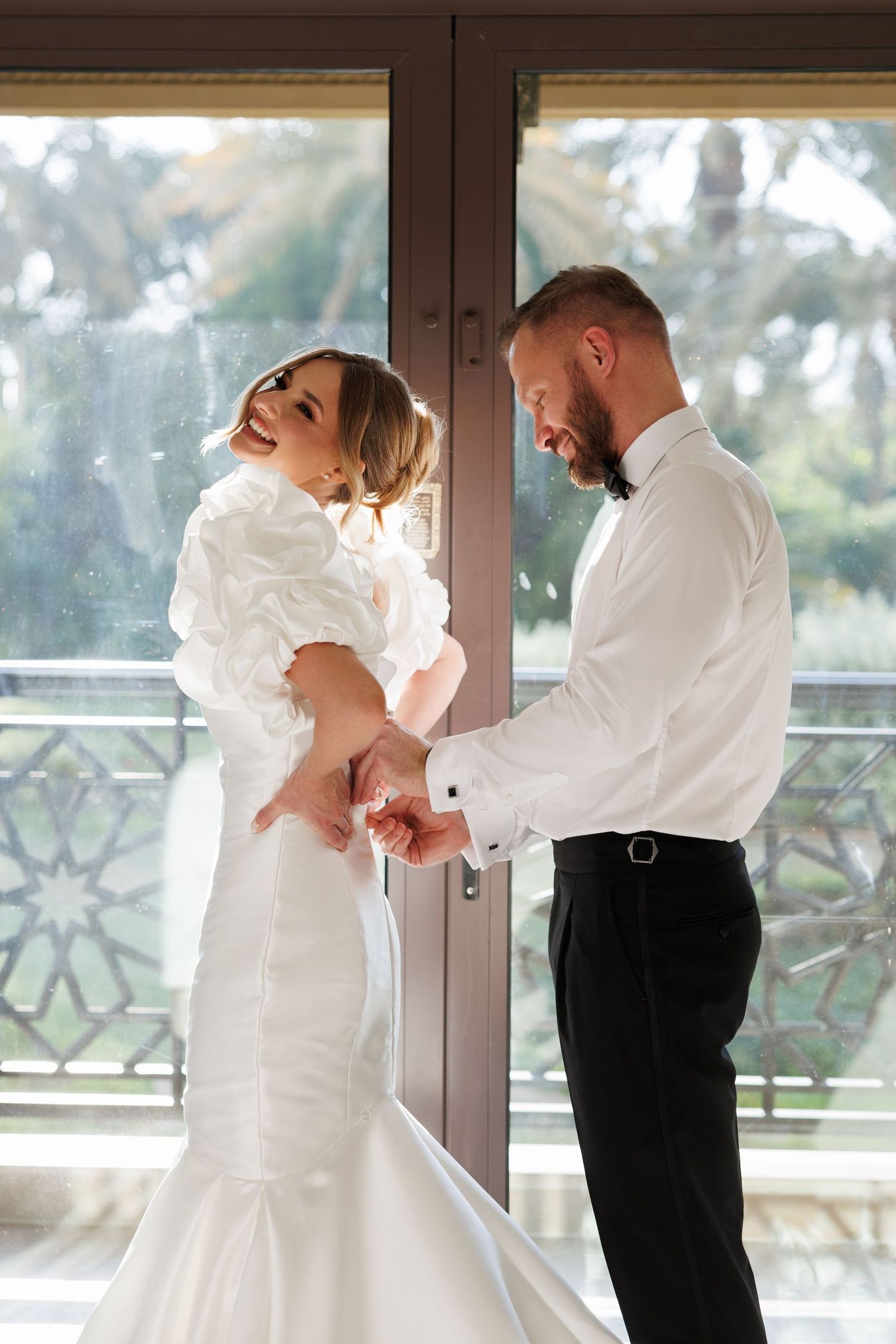 Romantic first look moment on balcony with tropical backdrop.