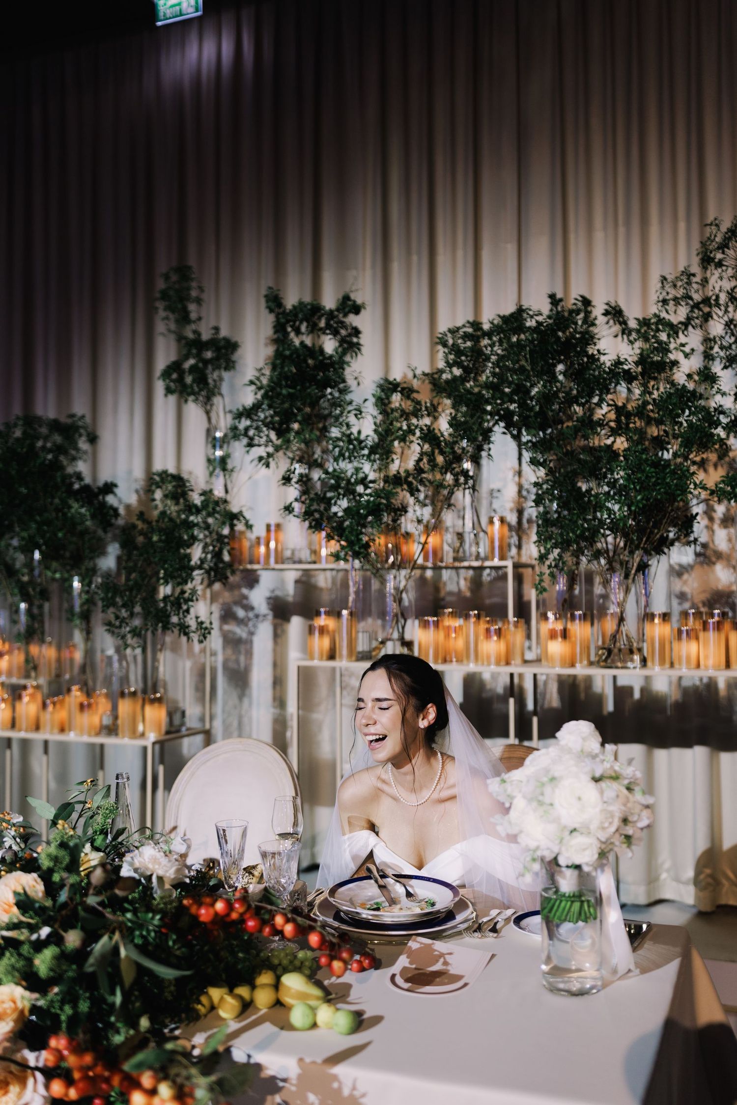 Modern wedding reception table setup with white linens, floral centerpieces and ambient lighting.