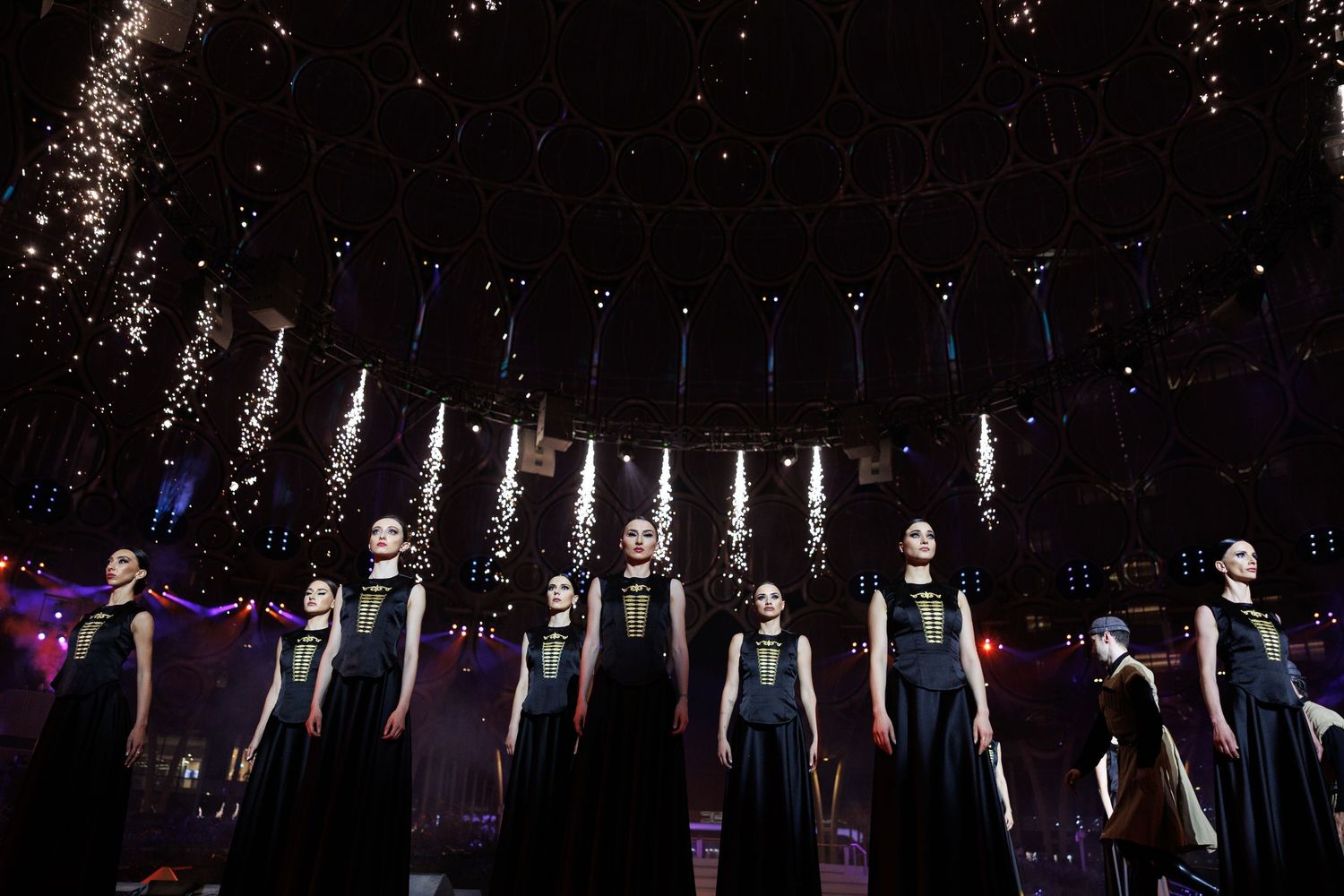 Stage performers taking a bow during curtain call with dramatic lighting.