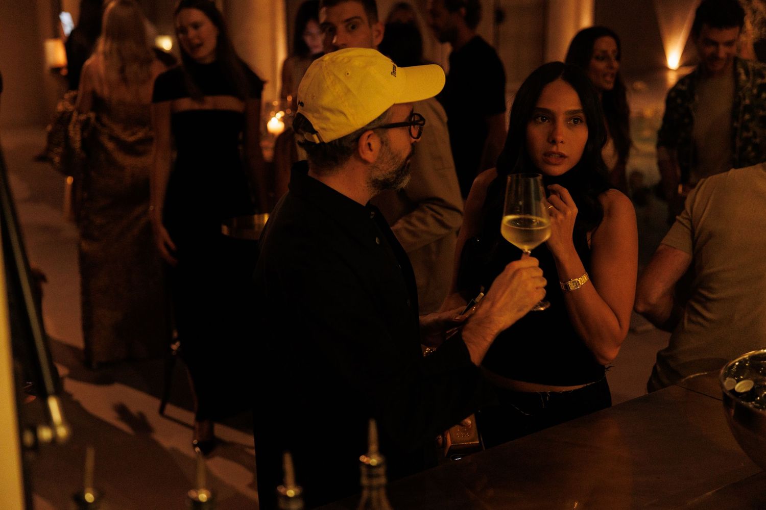 Crowded nighttime social gathering with ambient lighting and people mingling.