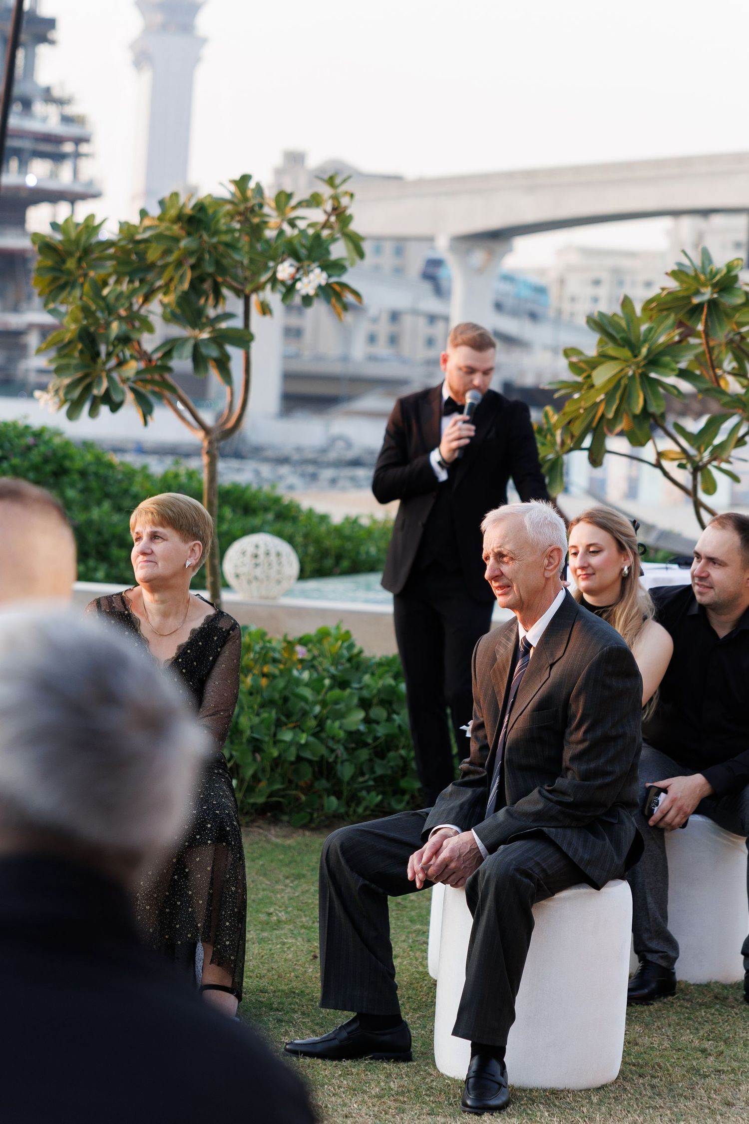 Wedding guests relaxing on white outdoor furniture during an evening reception.