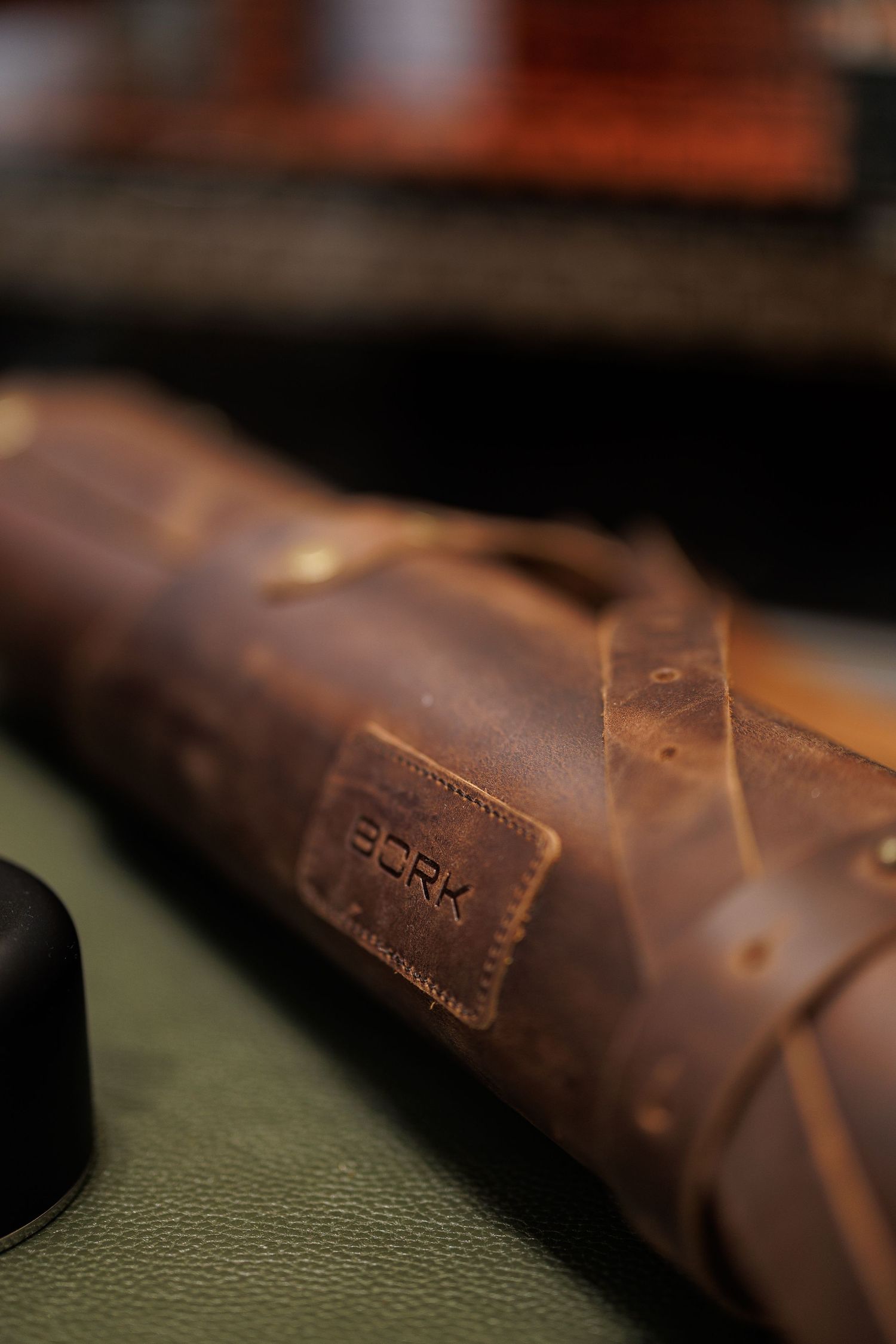 Close-up detail of a brown leather item with embossed PCRK branding on textured surface.