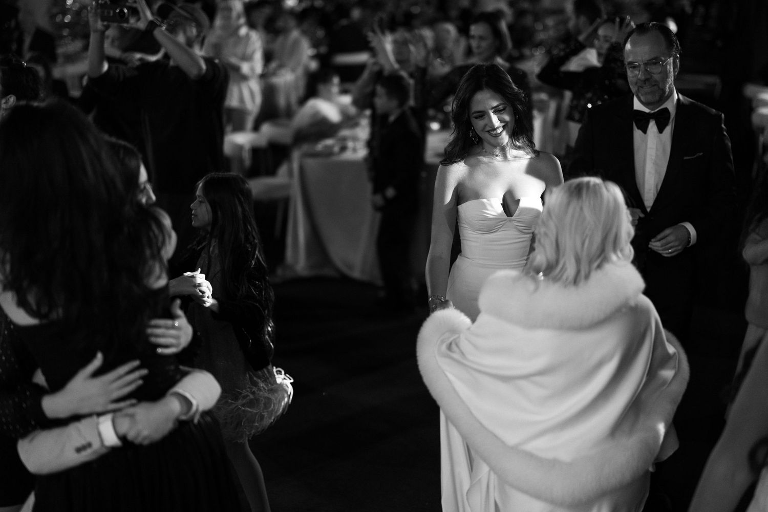 A couple shares a romantic dance at their wedding reception while guests look on from the background.