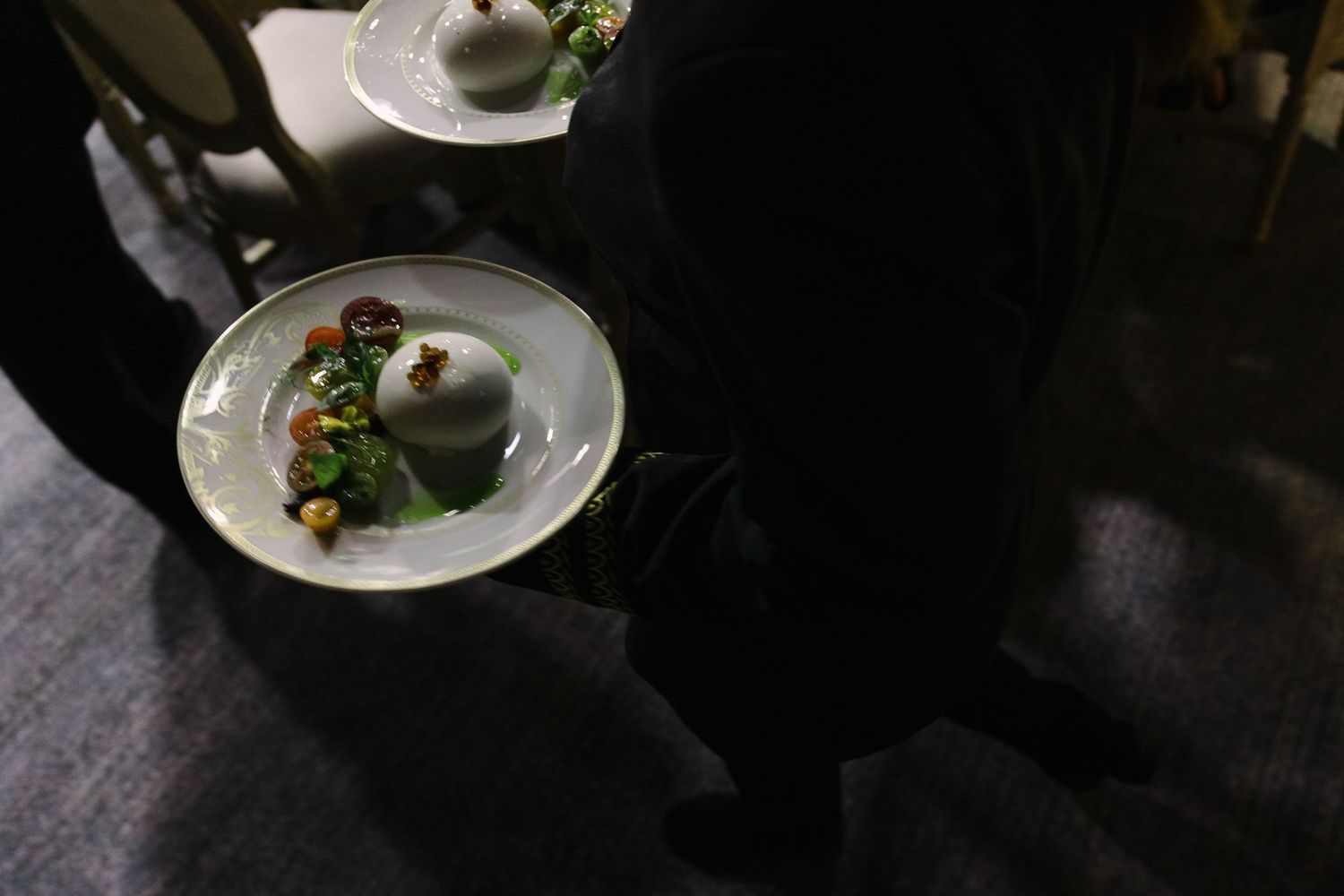 Artistically plated gourmet dish on white plate in dark moody lighting.
