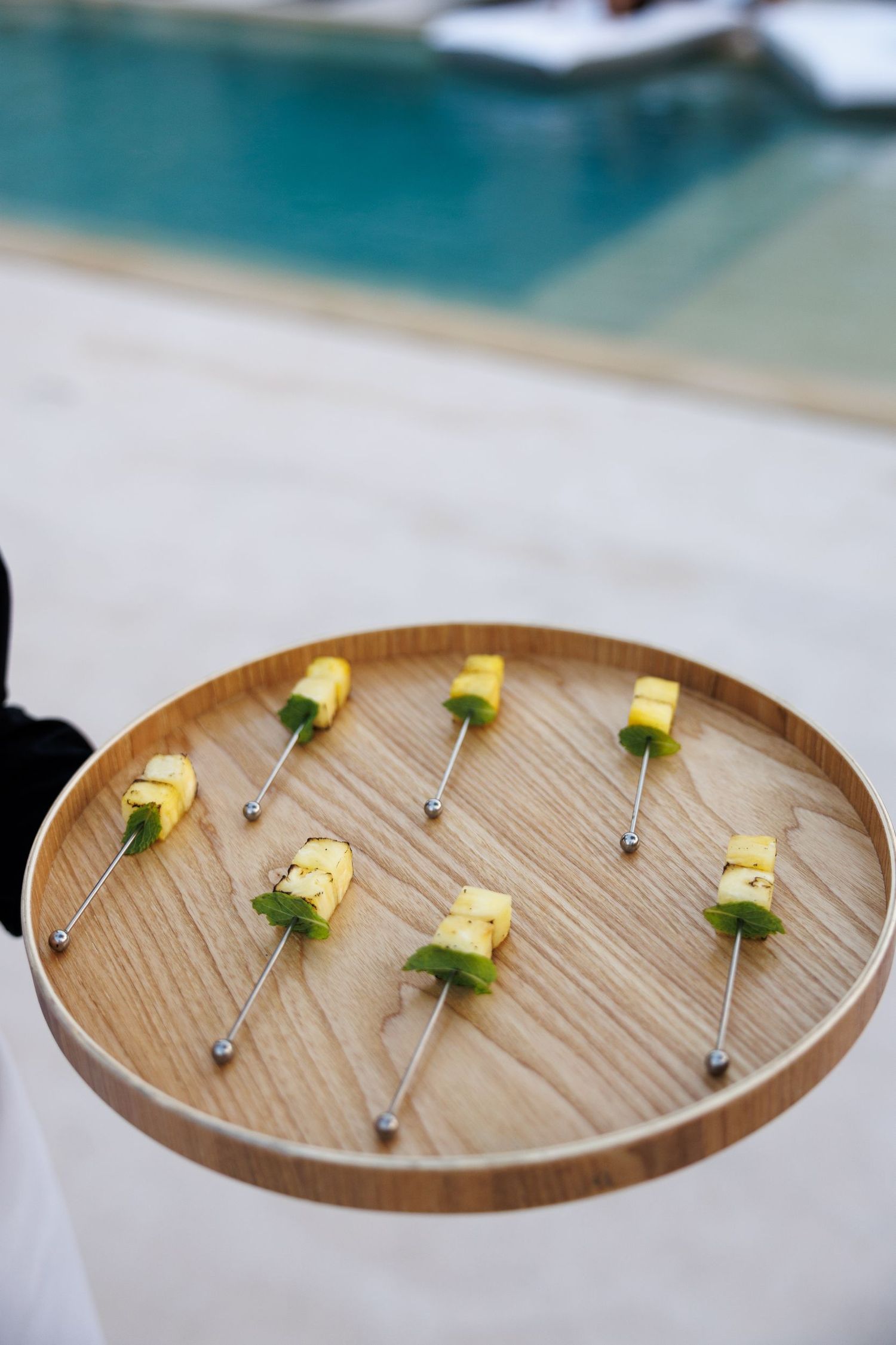 Wooden tray with small yellow appetizers arranged in a circular pattern.