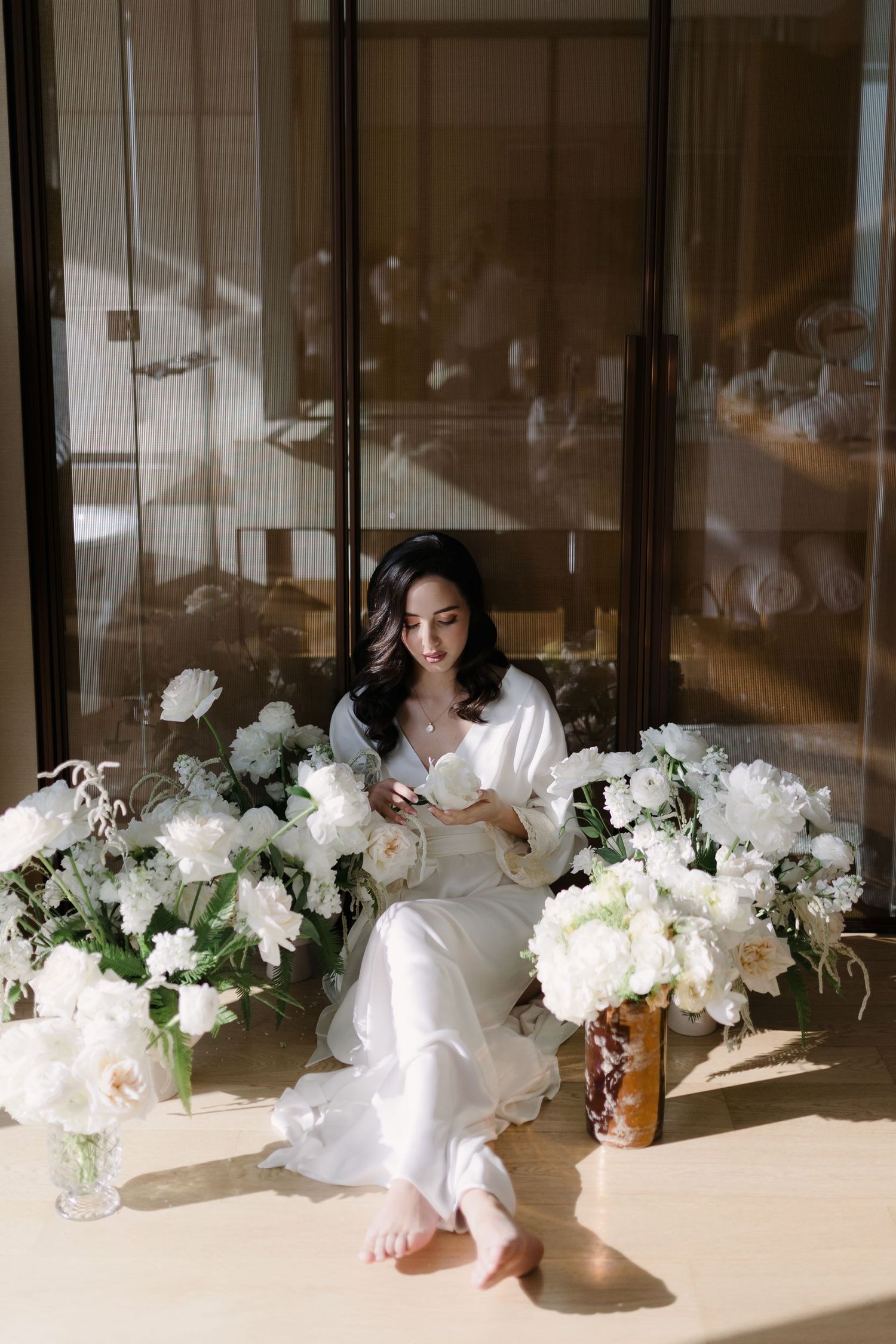 White floral arrangements displayed along floor with window light creating shadows.
