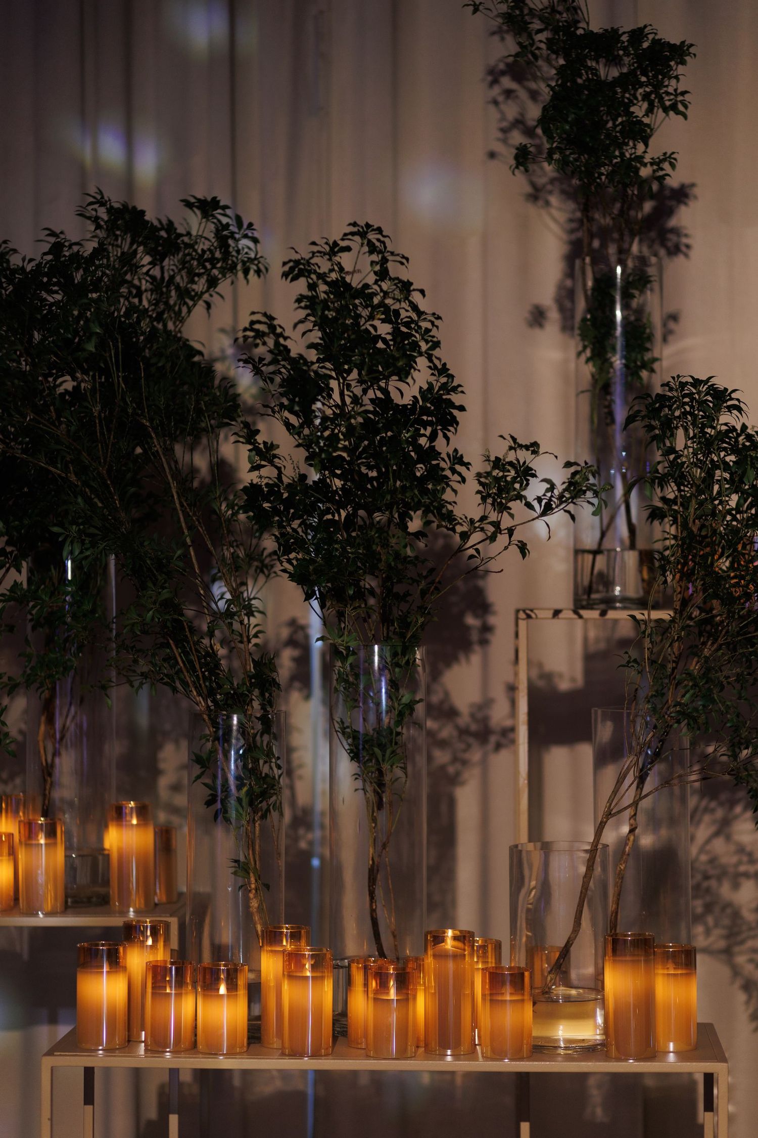Atmospheric wedding decor featuring glowing candles and greenery arrangements.