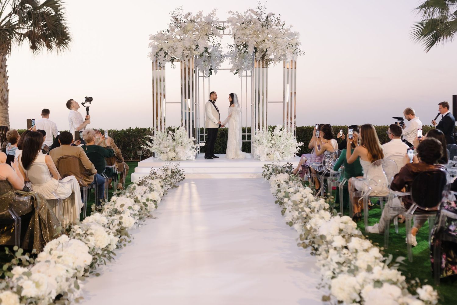 Panoramic view of wedding ceremony setup with white floral arrangements and columns.