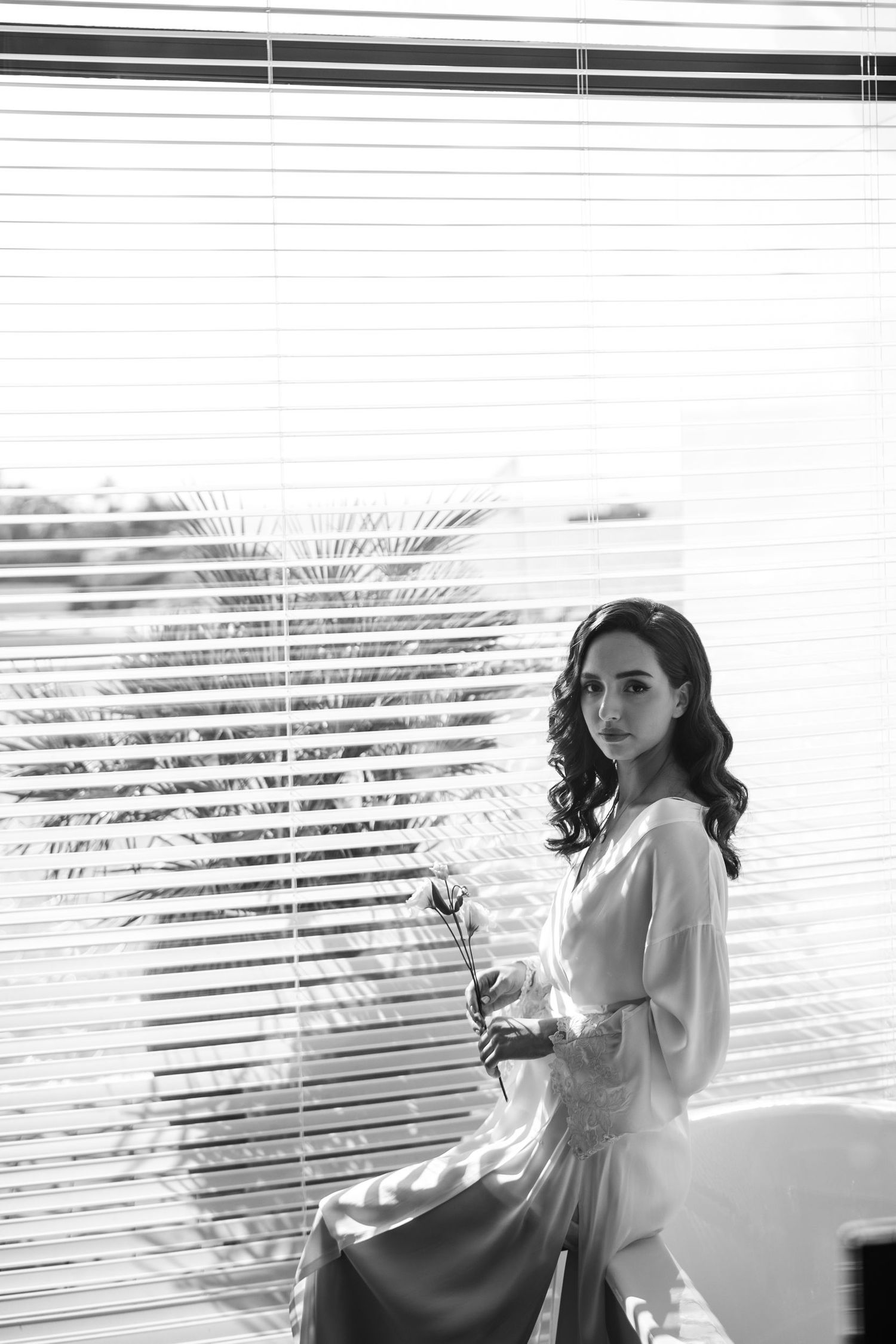 Black and white series of dreamy poses by window with venetian blind shadows.