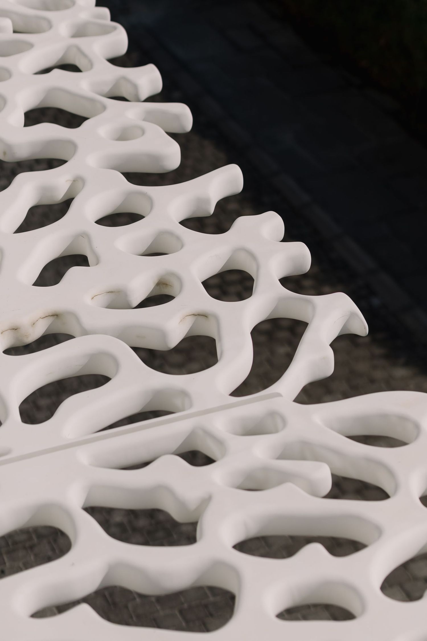 Abstract white architectural detail with organic honeycomb pattern against dark background.