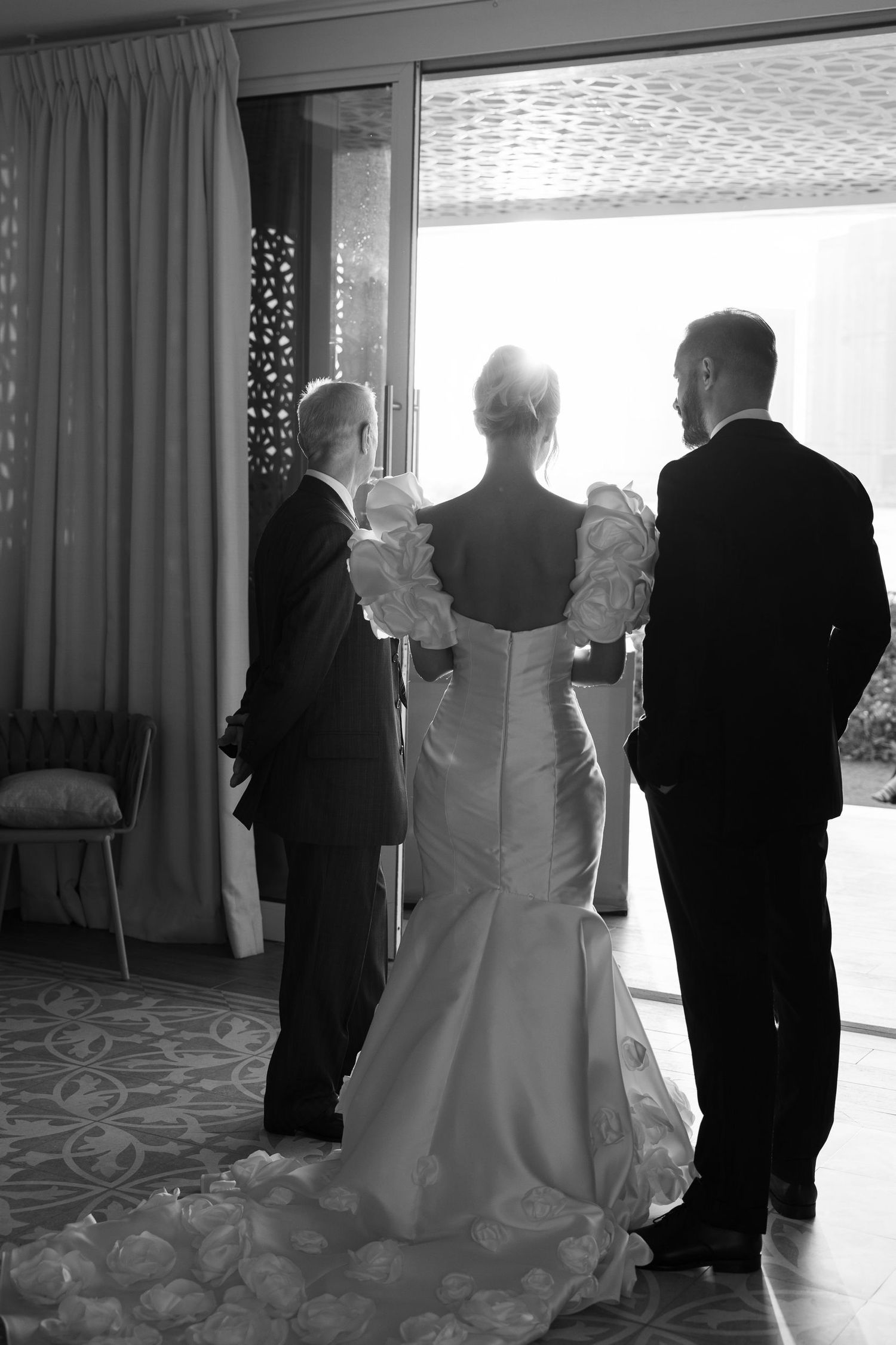 Black and white wedding preparation photo showing final dress adjustments.