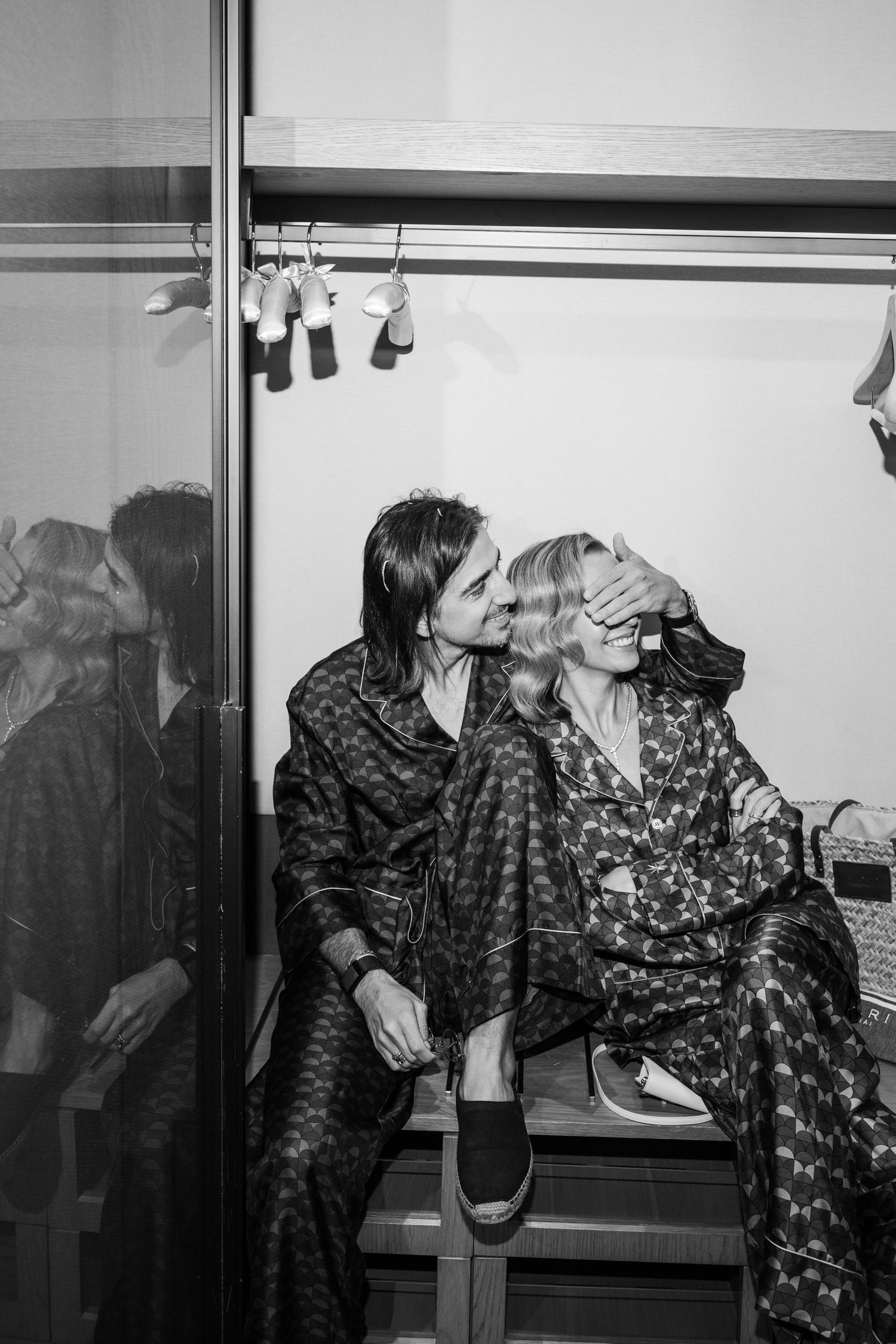 Group in matching dark patterned outfits pose casually in black and white photo.