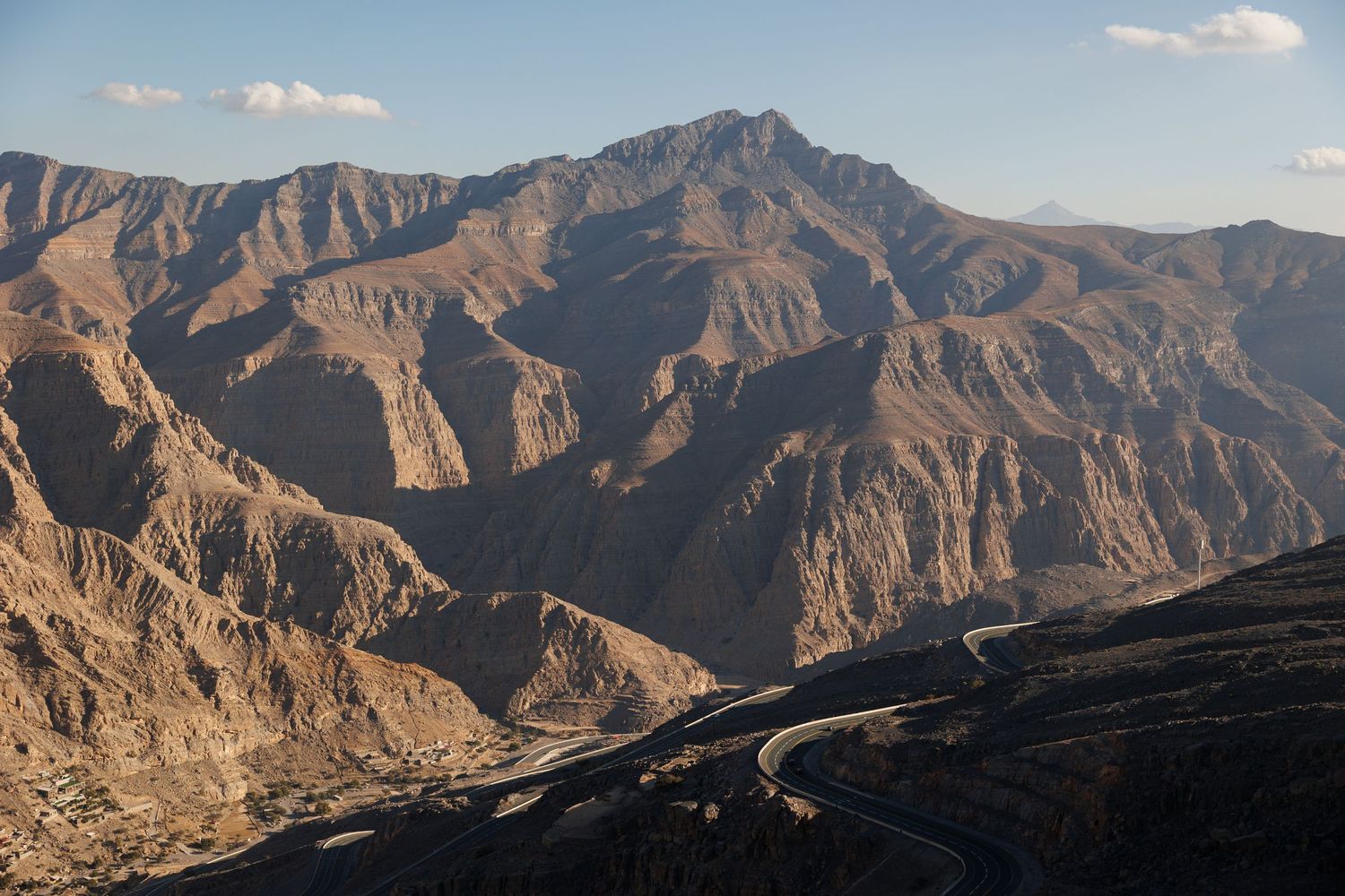 Panoramic view of rugged mountain ranges with dramatic peaks against a blue sky.