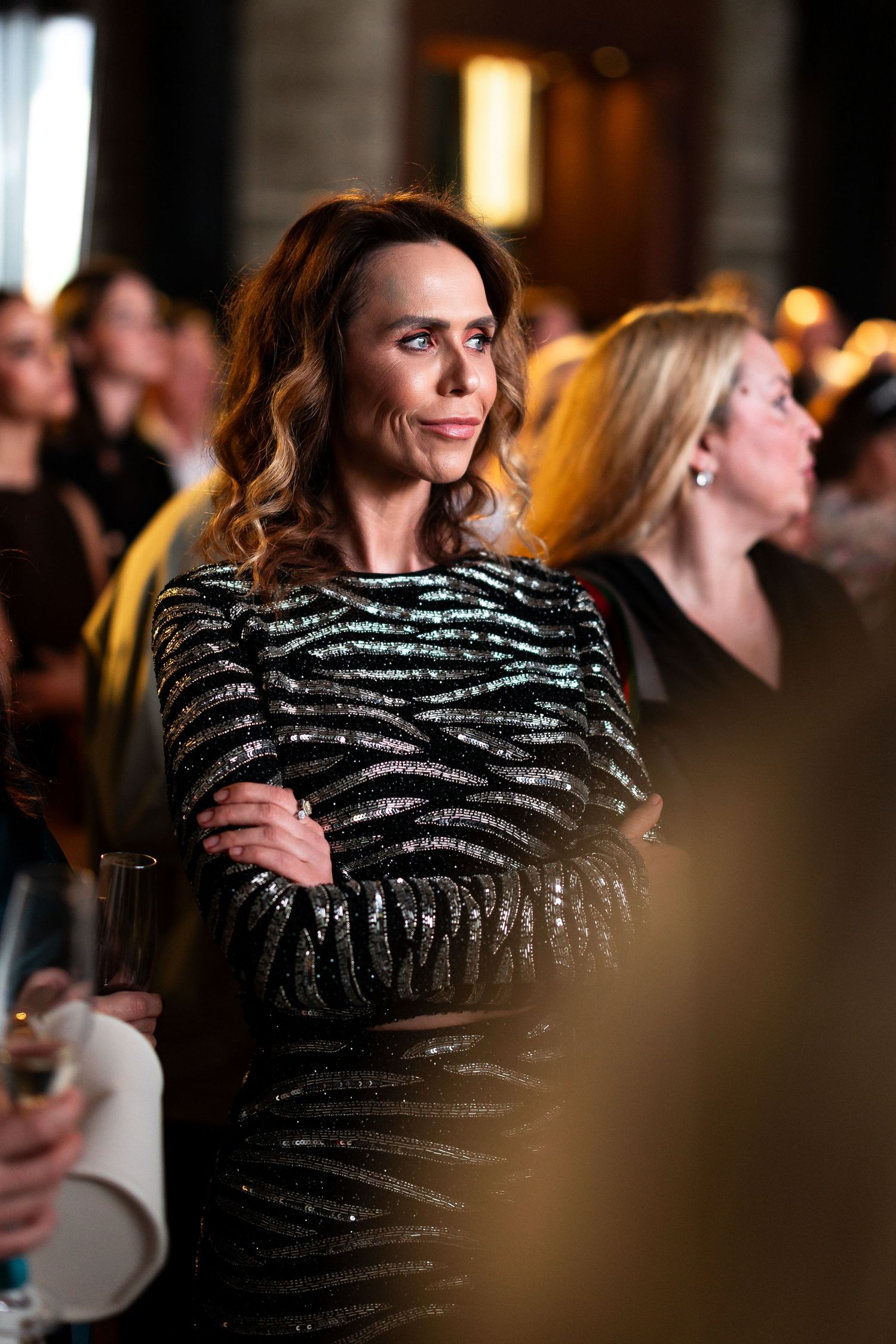 A person wearing a sparkly black and silver striped evening dress at a dimly lit social event.