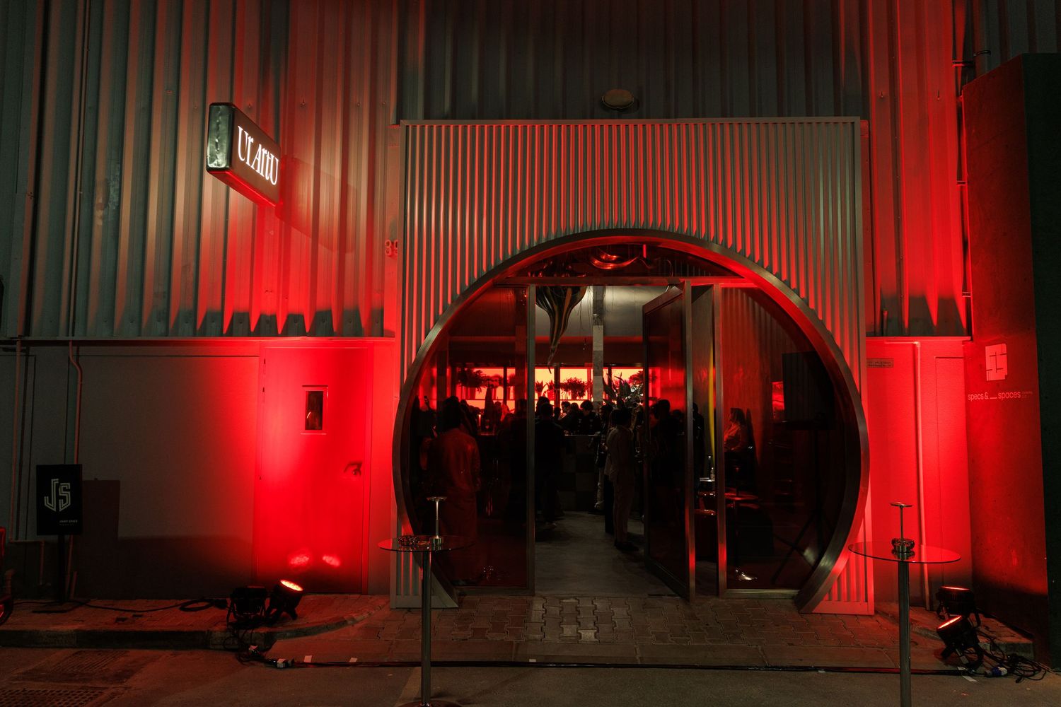 A series of dark concert venue interiors illuminated with dramatic red lighting and vertical architectural elements.
