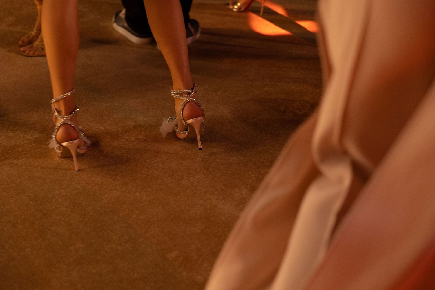 Close-up of strappy high heels on dance floor at formal event.