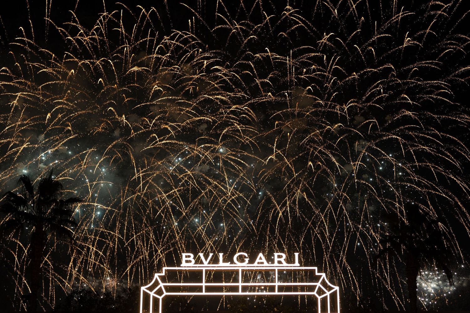 Spectacular fireworks display against night sky with architectural structure silhouette.
