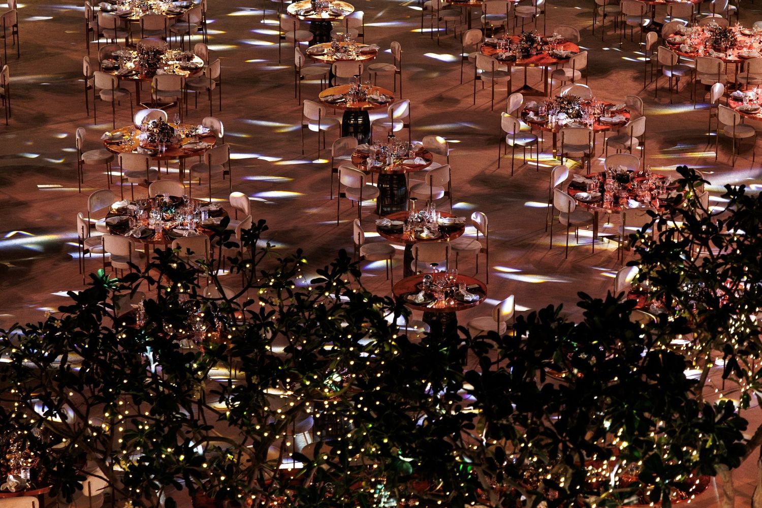 Aerial view of an elegant event space with tables and decorative lighting creating a warm ambiance.