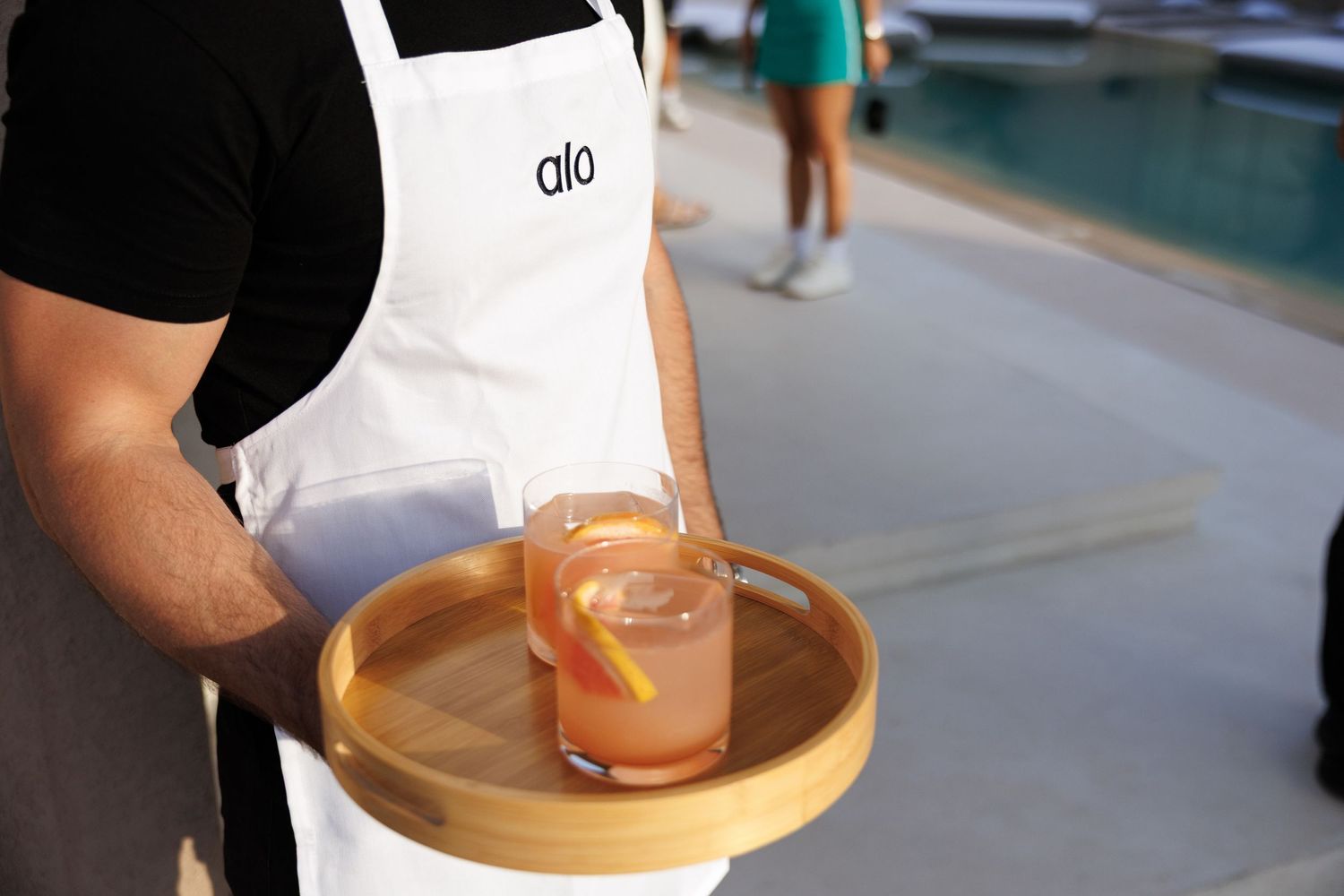 Wooden serving tray with appetizers being presented poolside at a wellness retreat.