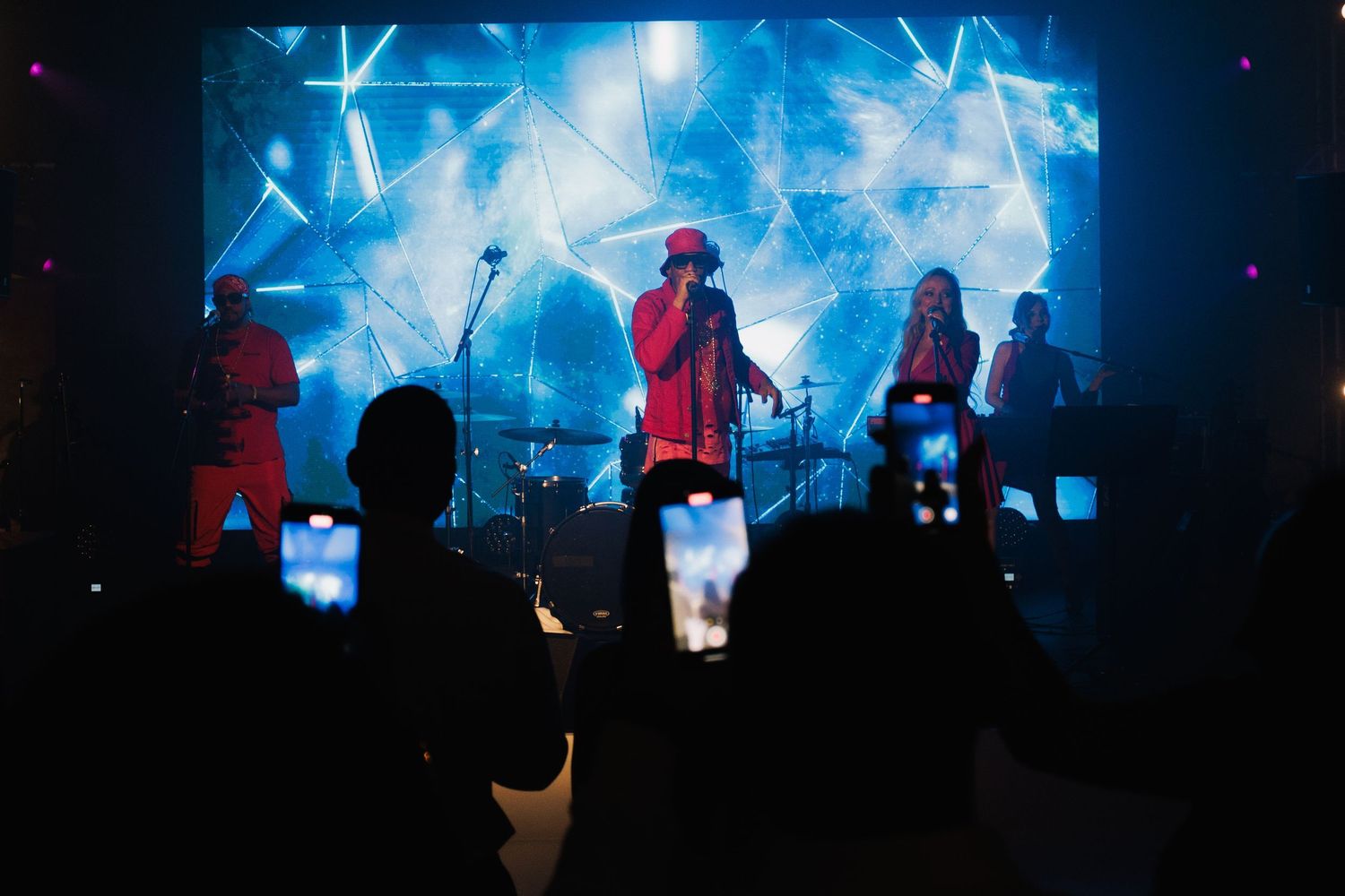Concert stage illuminated with blue lights and silhouetted performers.