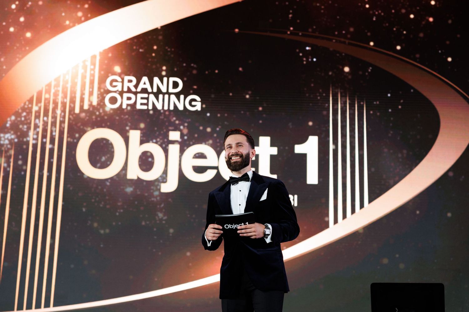 Elegant grand opening event signage with dramatic lighting and silhouetted figures.