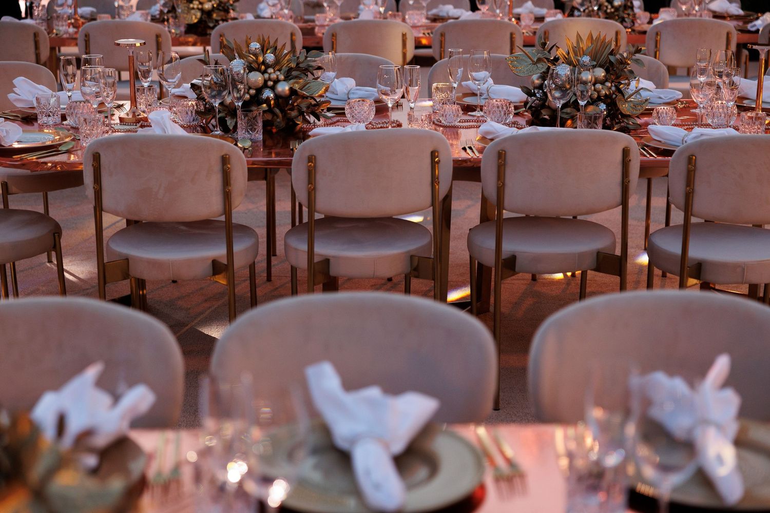Elegant dining room setup with white floral centerpieces and upholstered chairs.