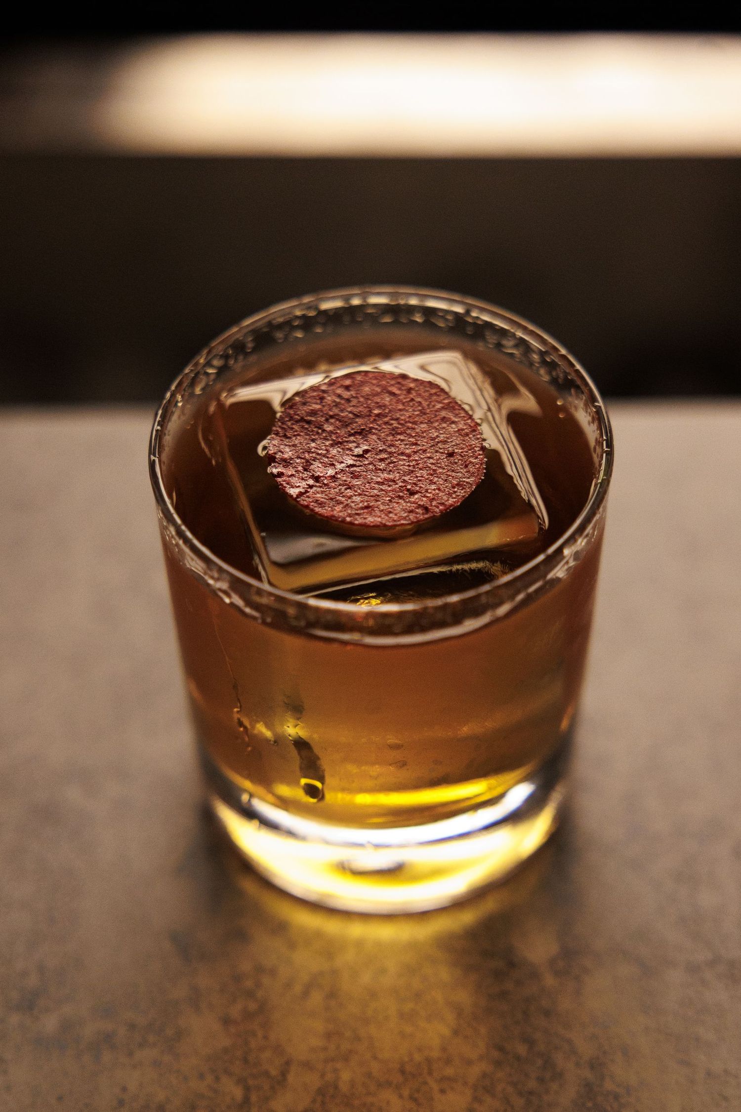 A craft cocktail with a chocolate garnish in a lowball glass.