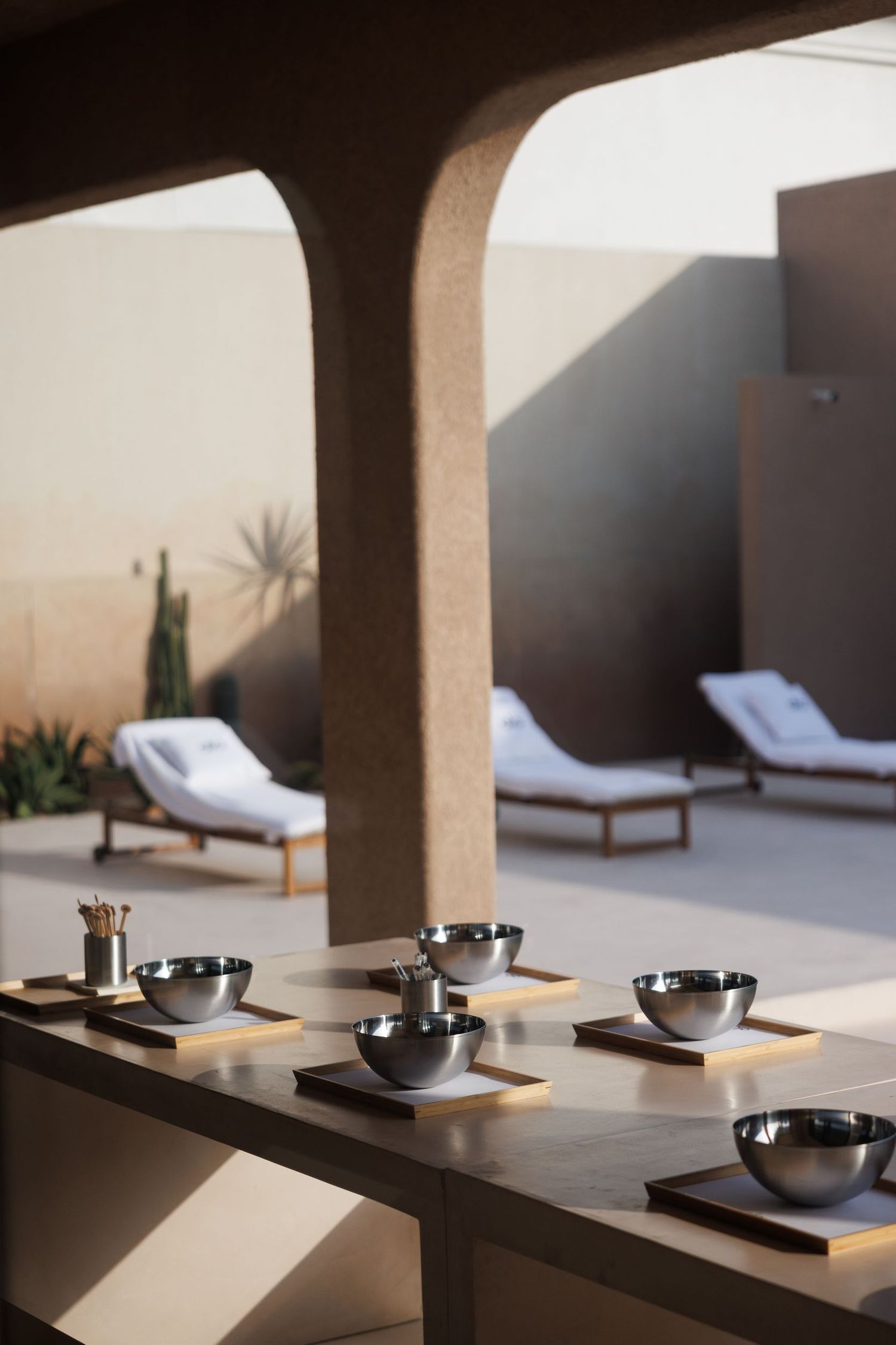 Outdoor spa area with lounge chairs and serving bowls under arched architecture.