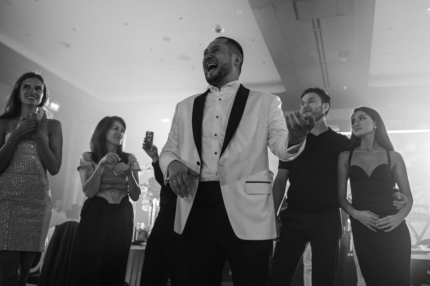 Black and white photo of wedding guests mingling and socializing at an elegant reception.