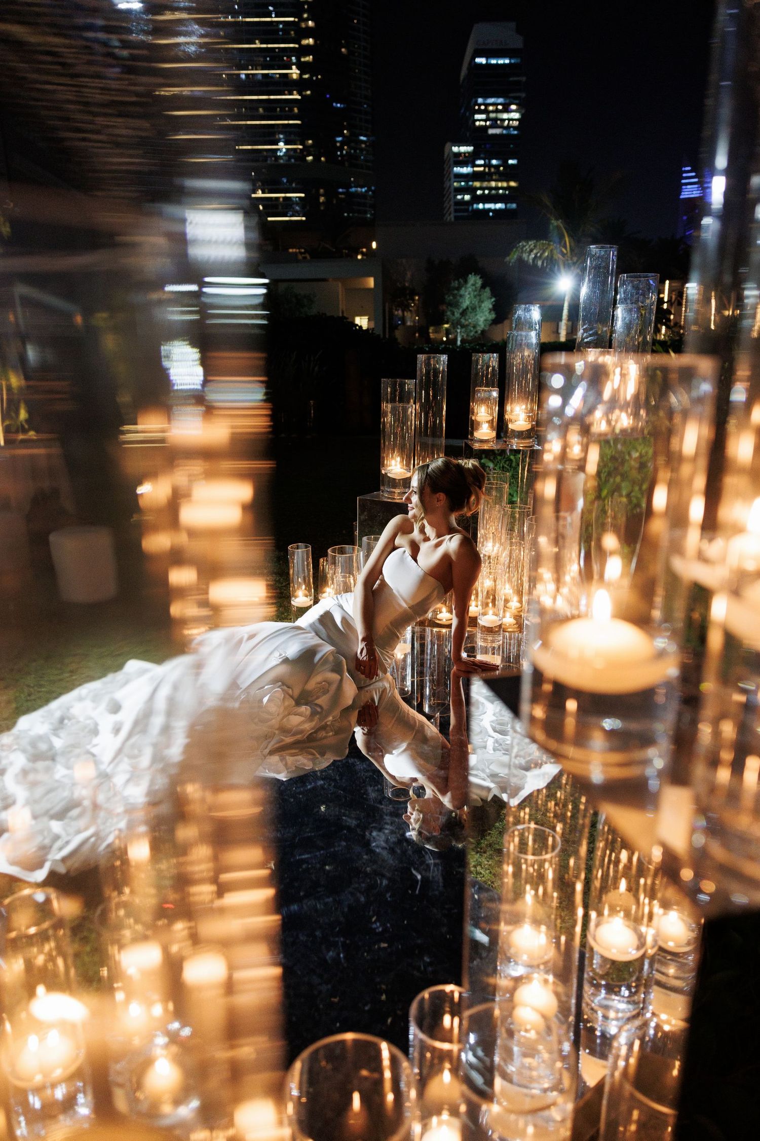 Atmospheric nighttime wedding scene with glowing candles and white gown.