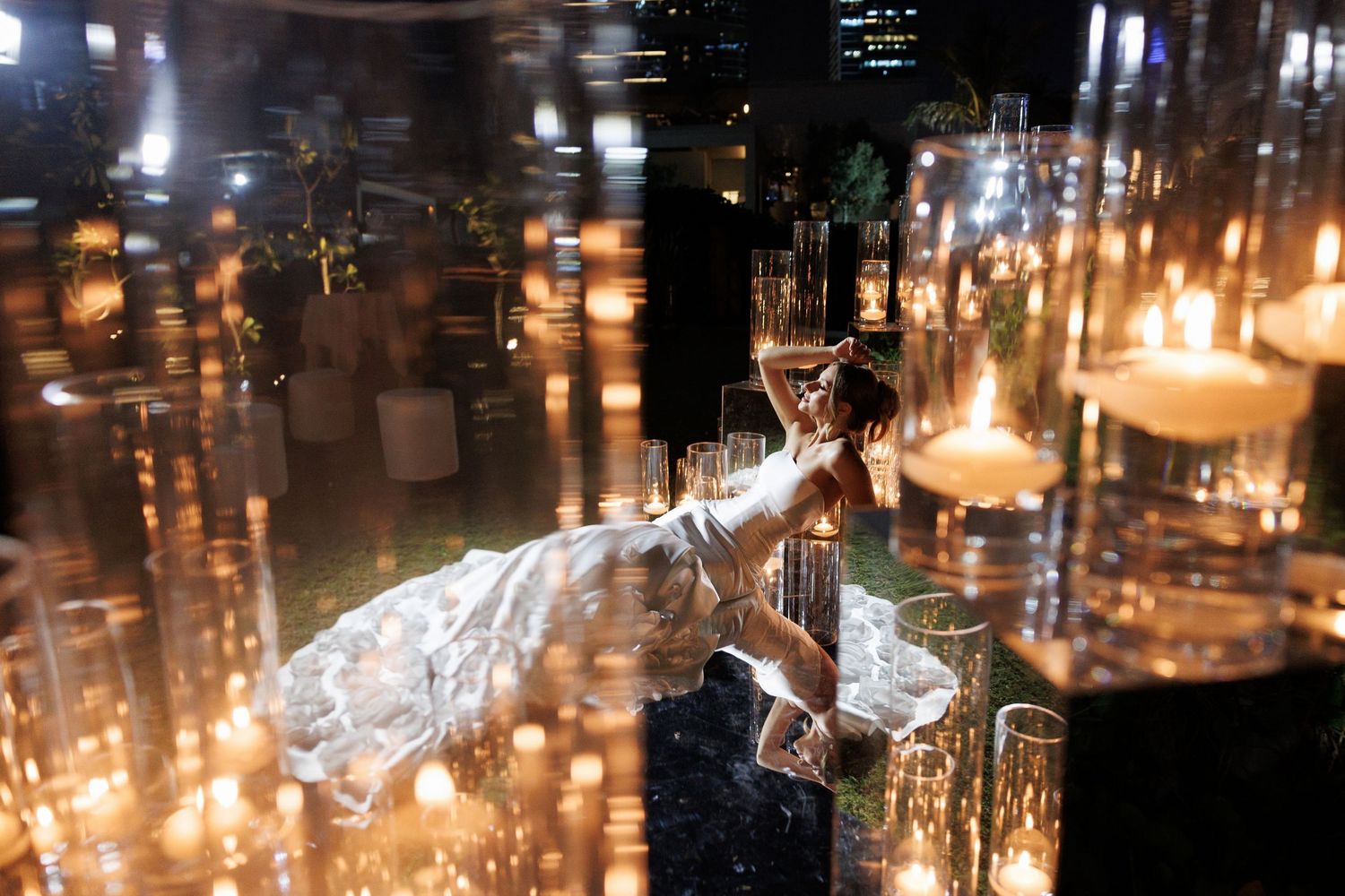 Romantic candlelit reception setting with multiple glass votives creating warm ambient lighting.