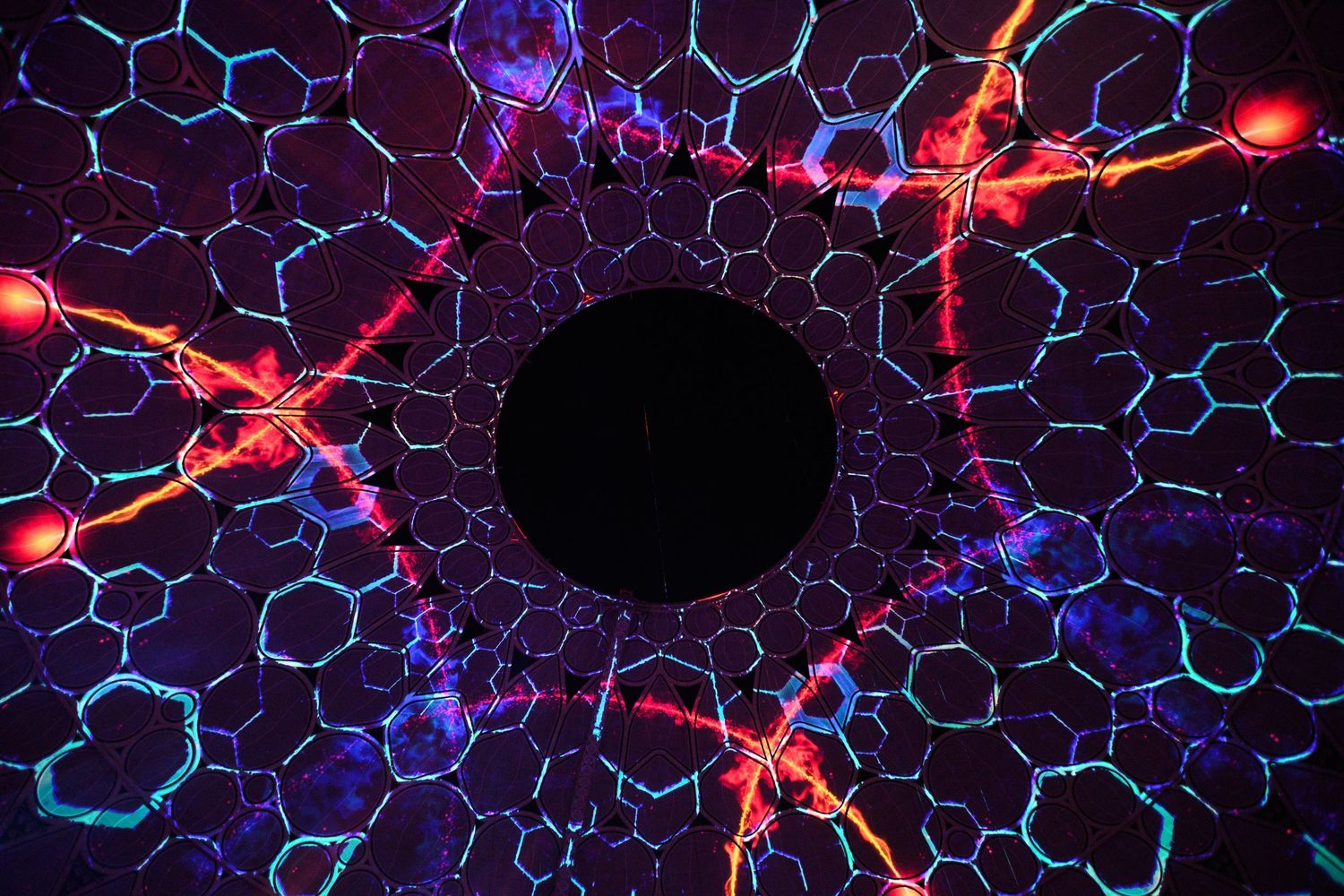 Abstract network of illuminated hexagonal patterns in purple and red lighting.