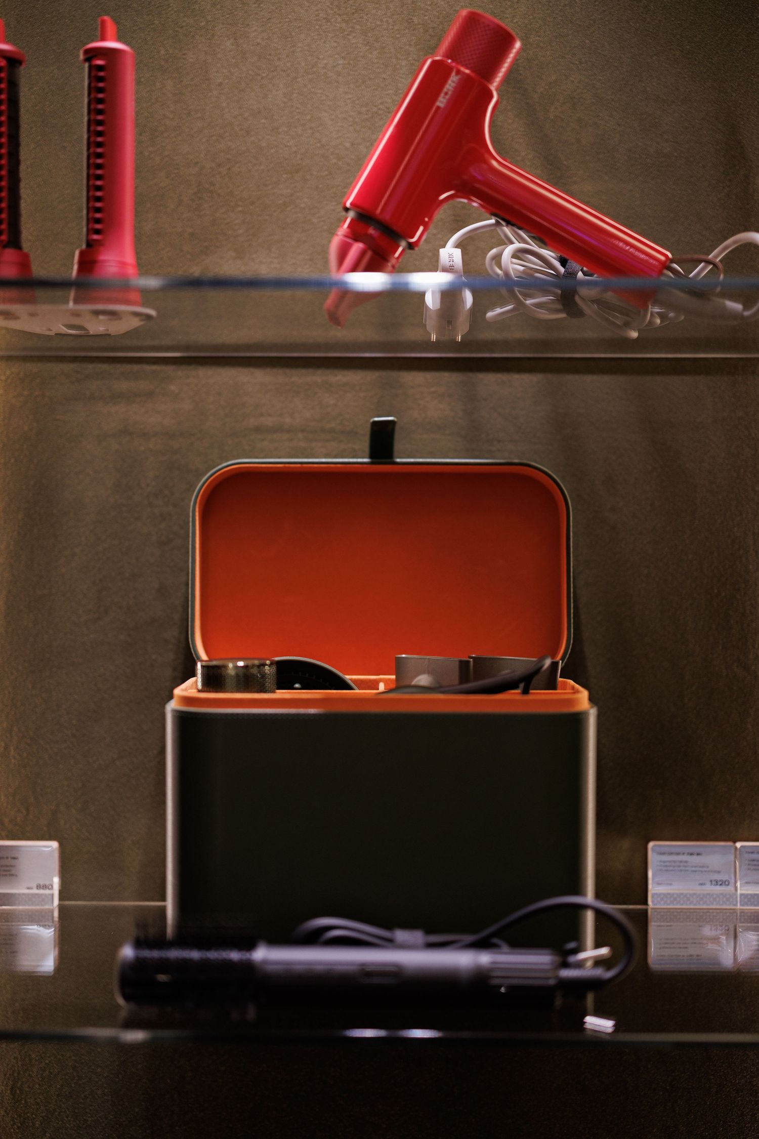 Red coffee maker components arranged on dark shelving.