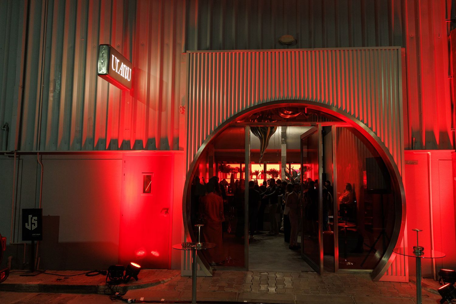 Industrial warehouse space bathed in red lighting with long corridor perspective.