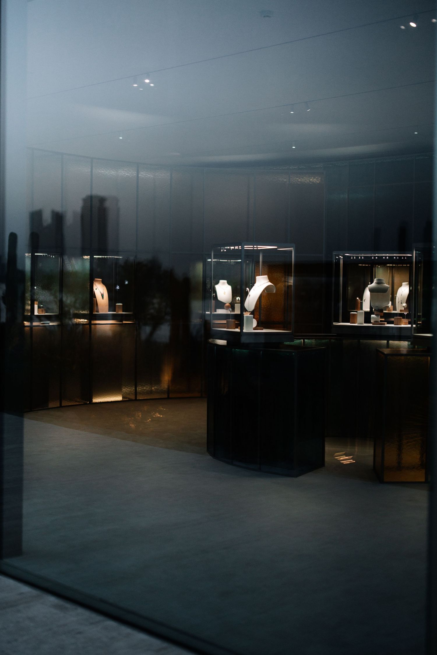 Illuminated display cases in a dark retail space showcase white clothing items against a moody backdrop.
