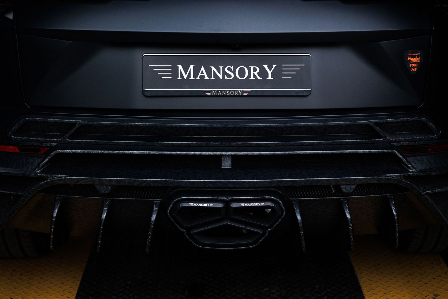 Close-up of Mansory luxury car badge on black vehicle exterior.