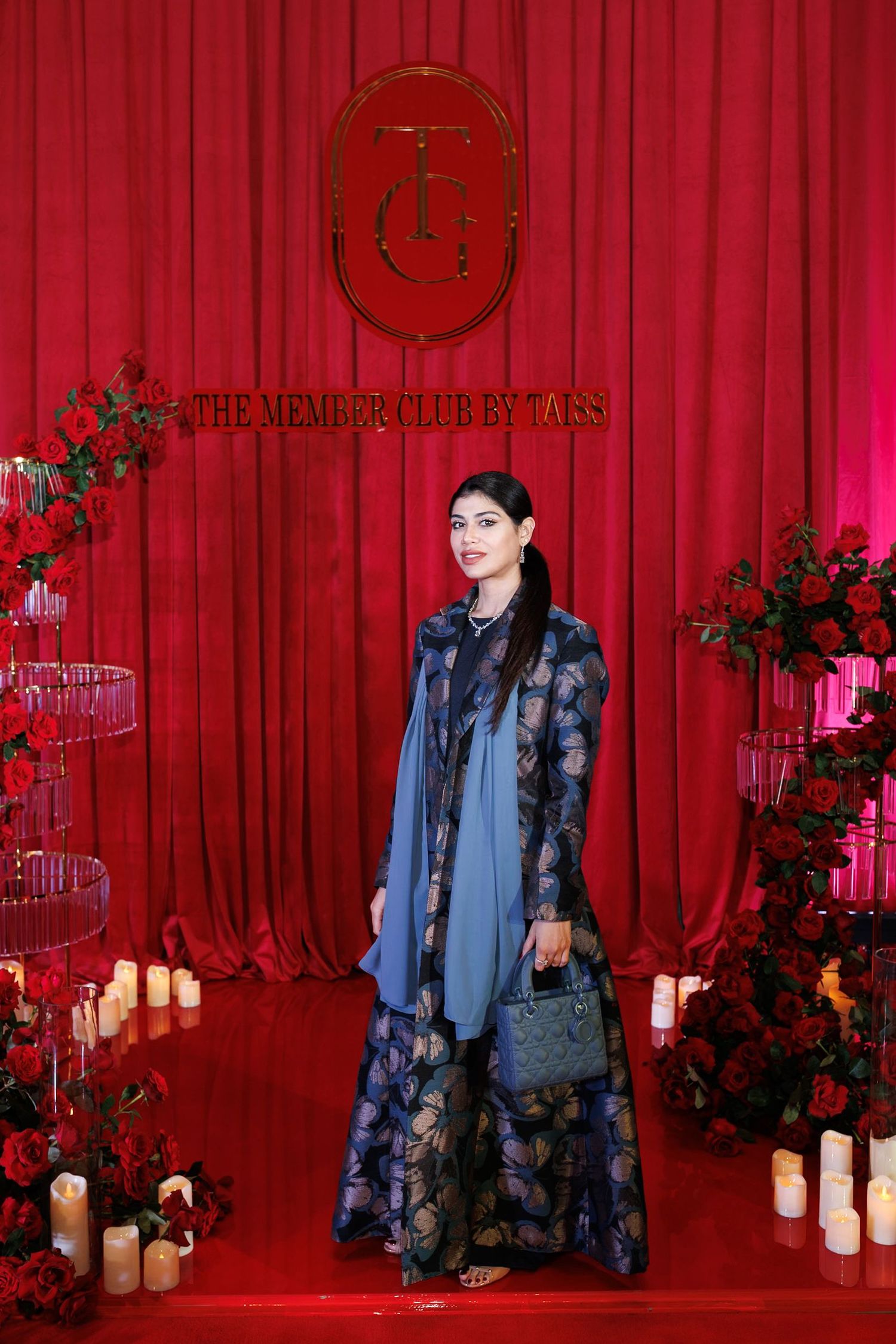 Fashion event setup with red curtain backdrop and floral decorations.