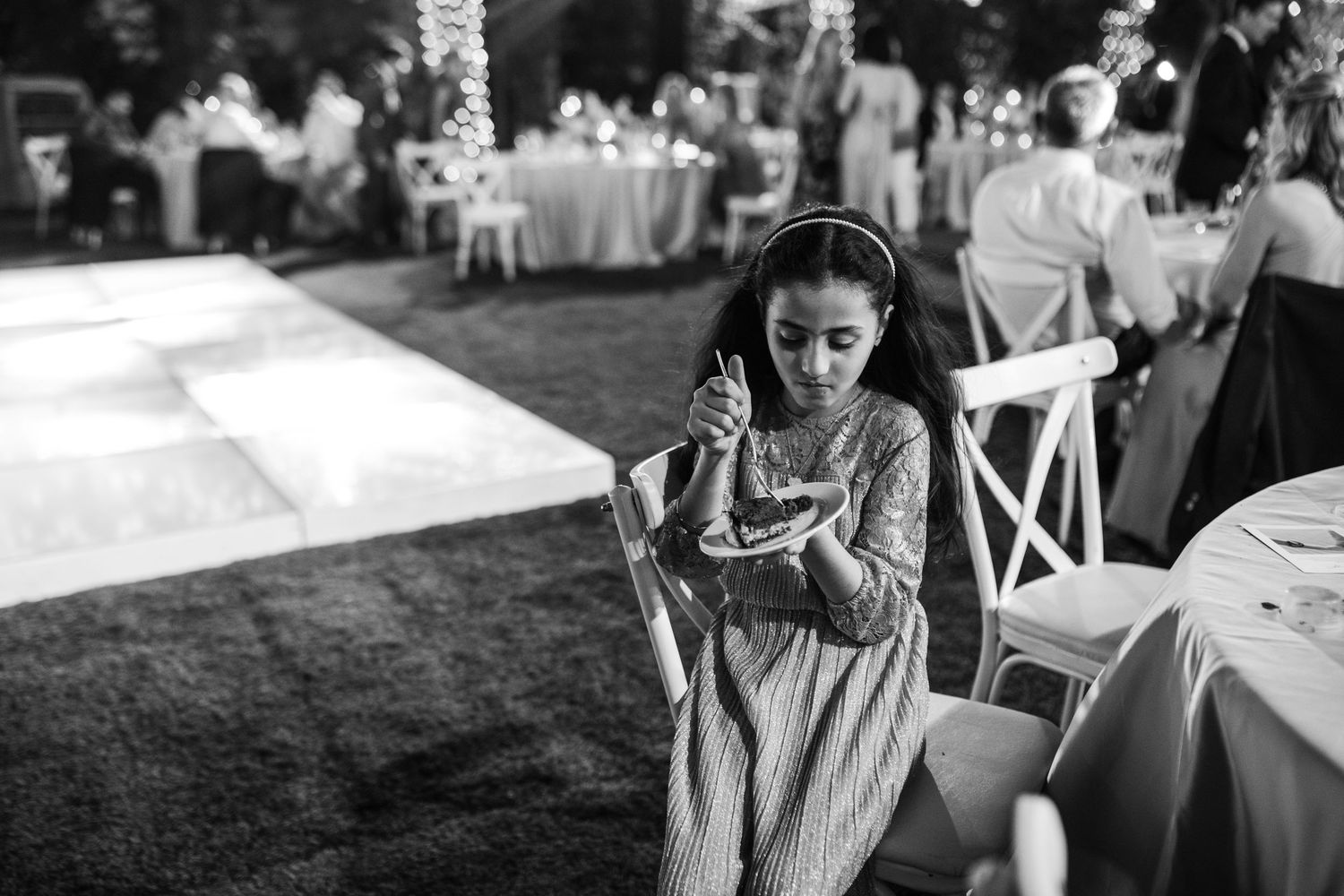 Wedding reception guests mingle at outdoor tables decorated with elegant place settings.