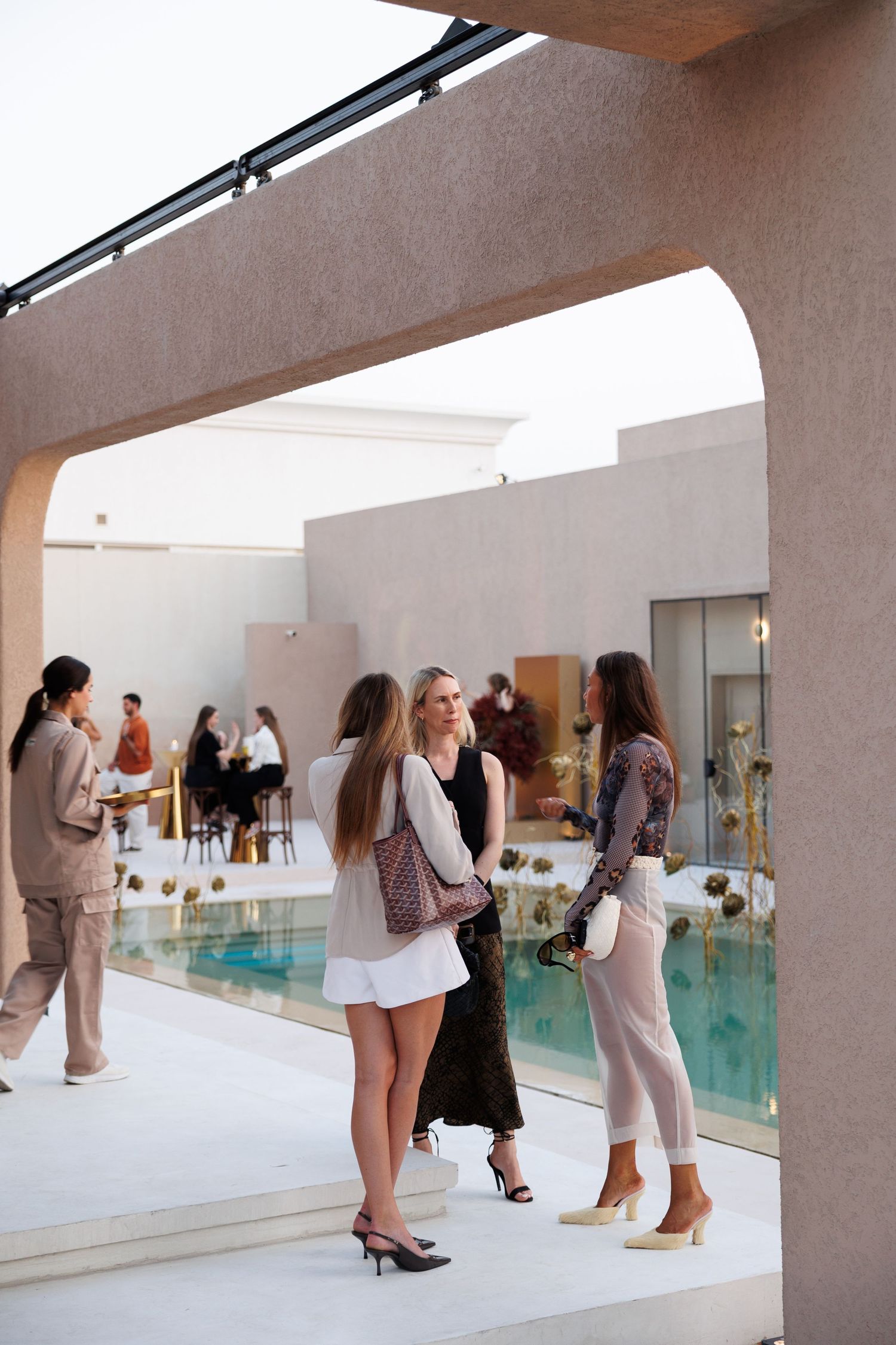 Group of people gathered in a modern space with white walls and an indoor pool.